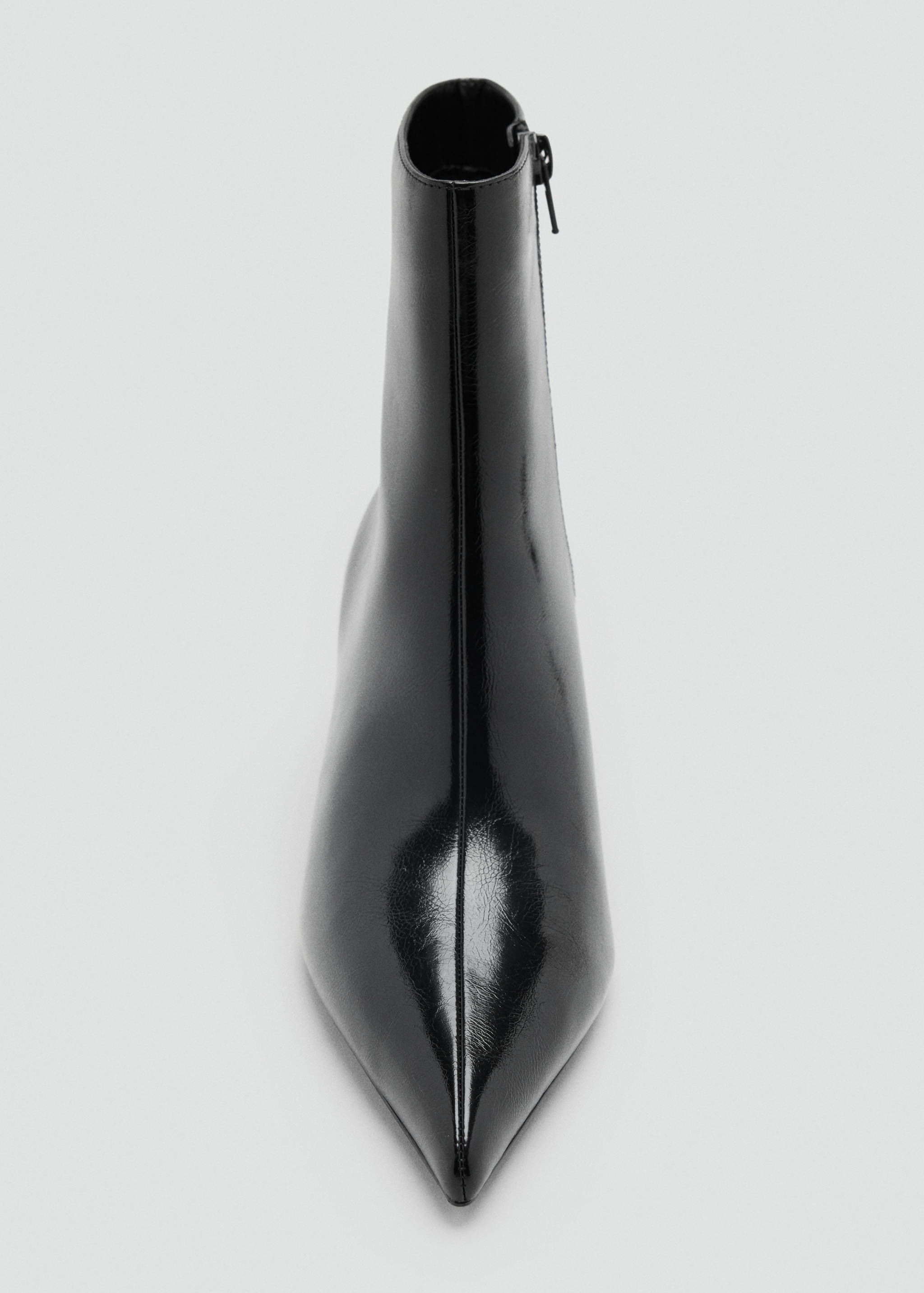 Close-up of a black patent ankle boot with a pointed toe.
