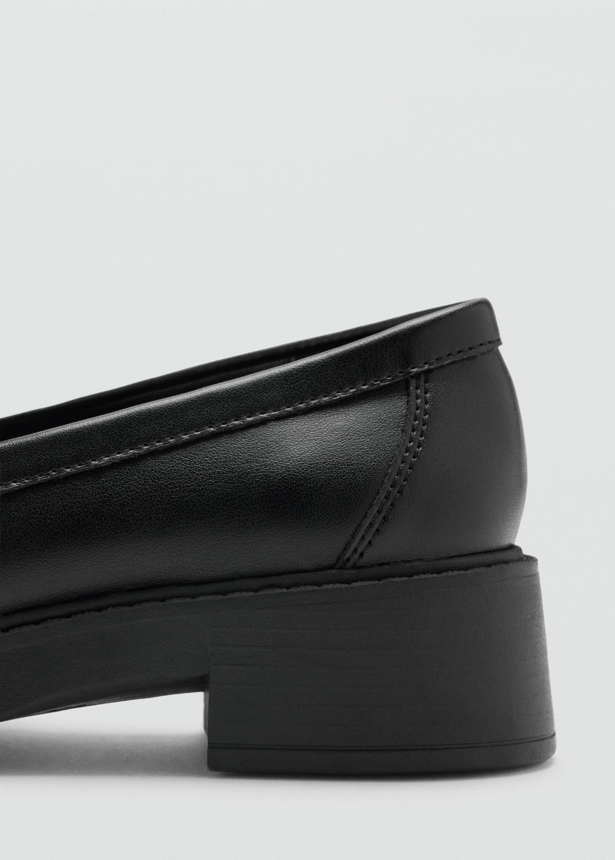Primer plano del detalle del talón en un zapato negro de polipiel.