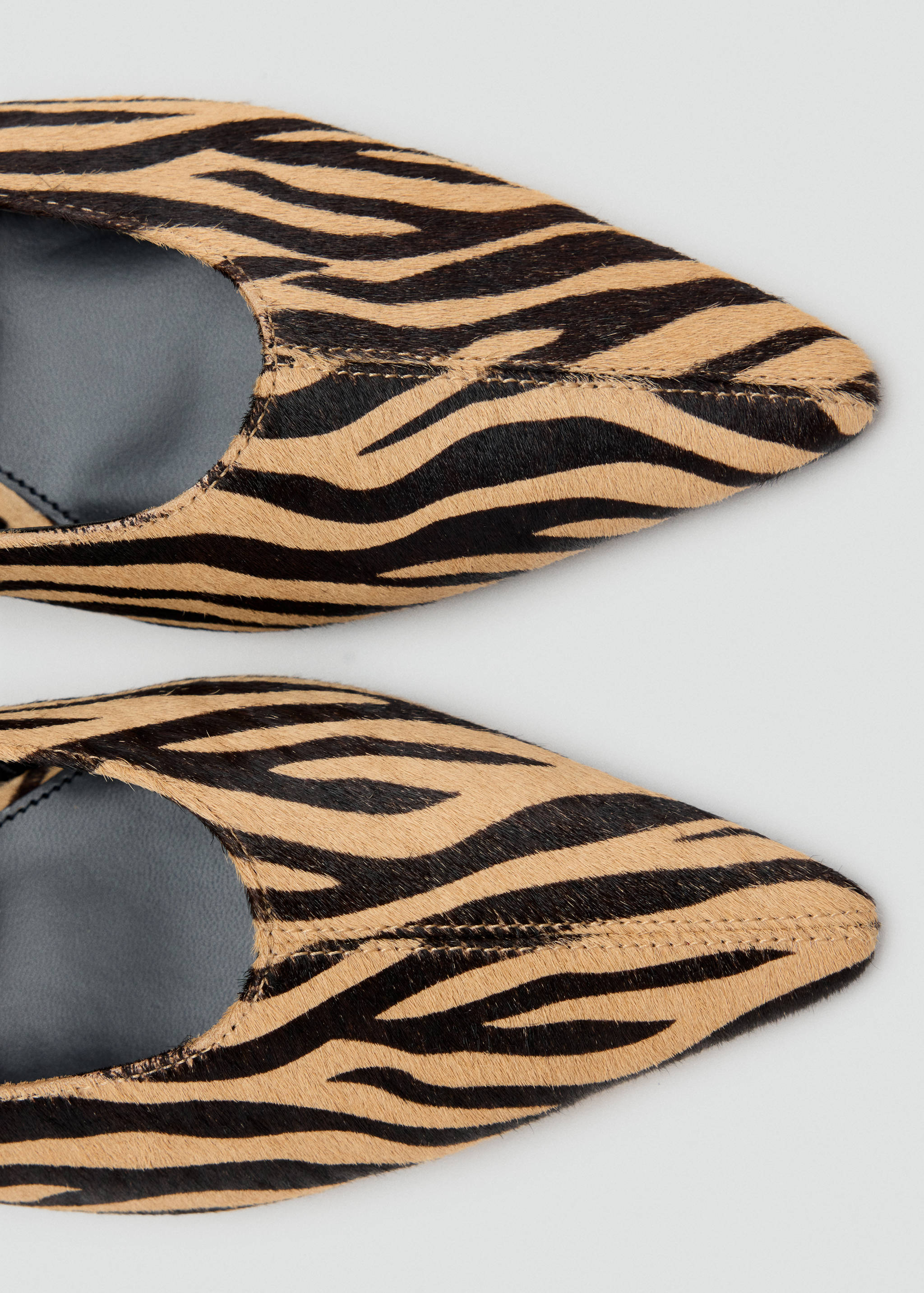 Close-up of pointed zebra-print shoes with a textured finish.