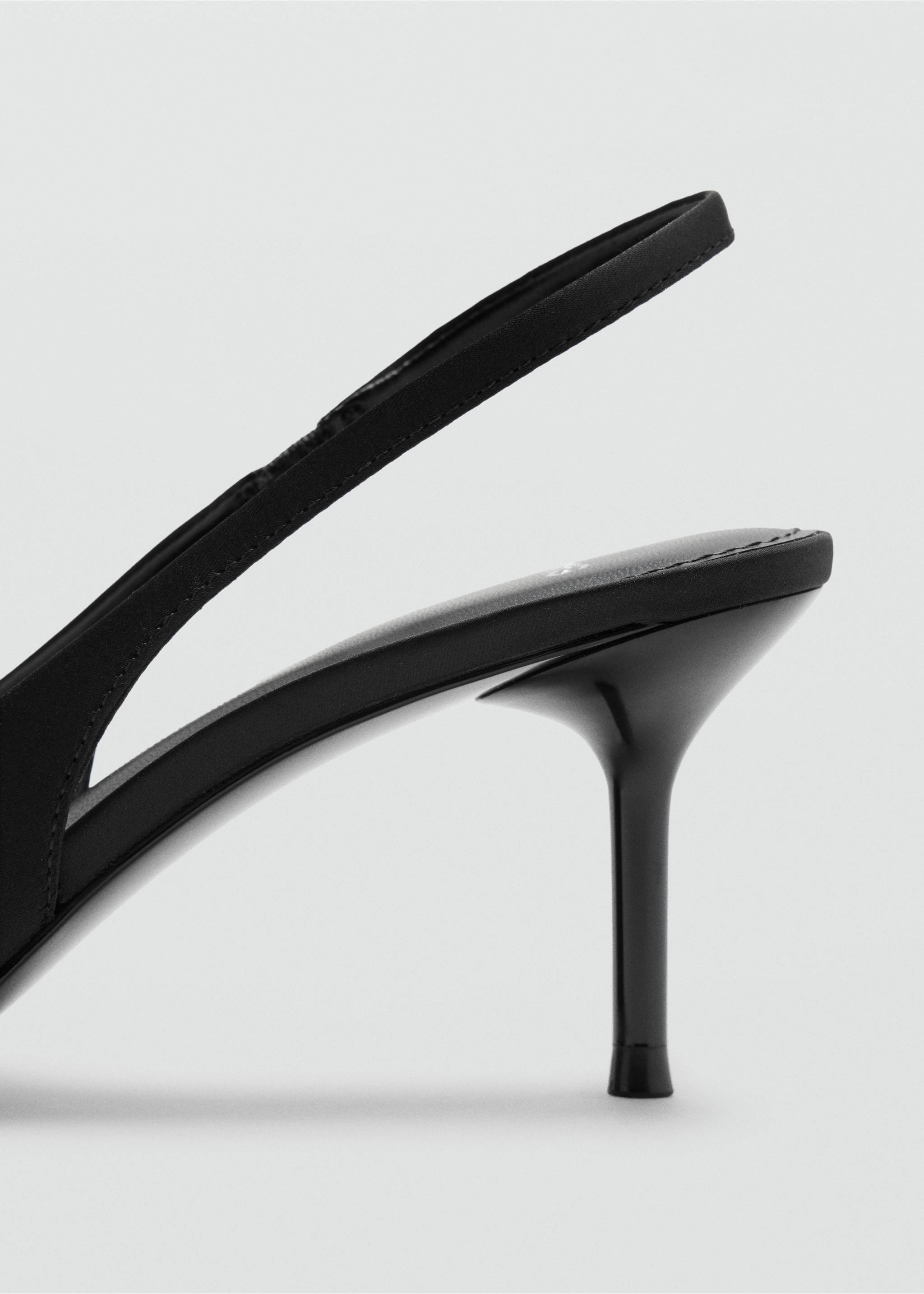 Close-up of a black shoe detail showing a glossy stiletto heel and slingback strap., Black. Ref: 47021353-00.