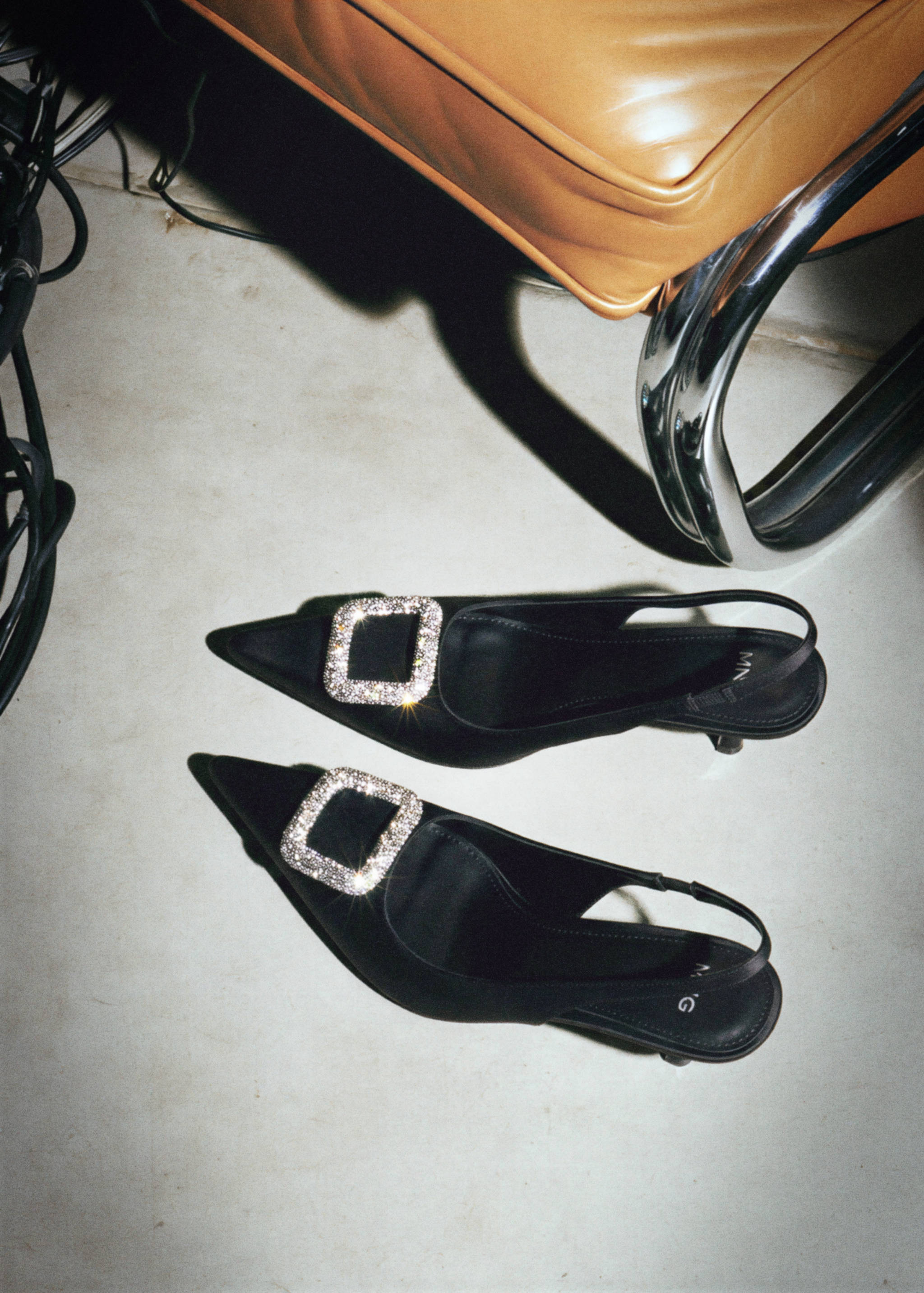 Black slingback shoes with pointed toes and rhinestone-embellished buckles.