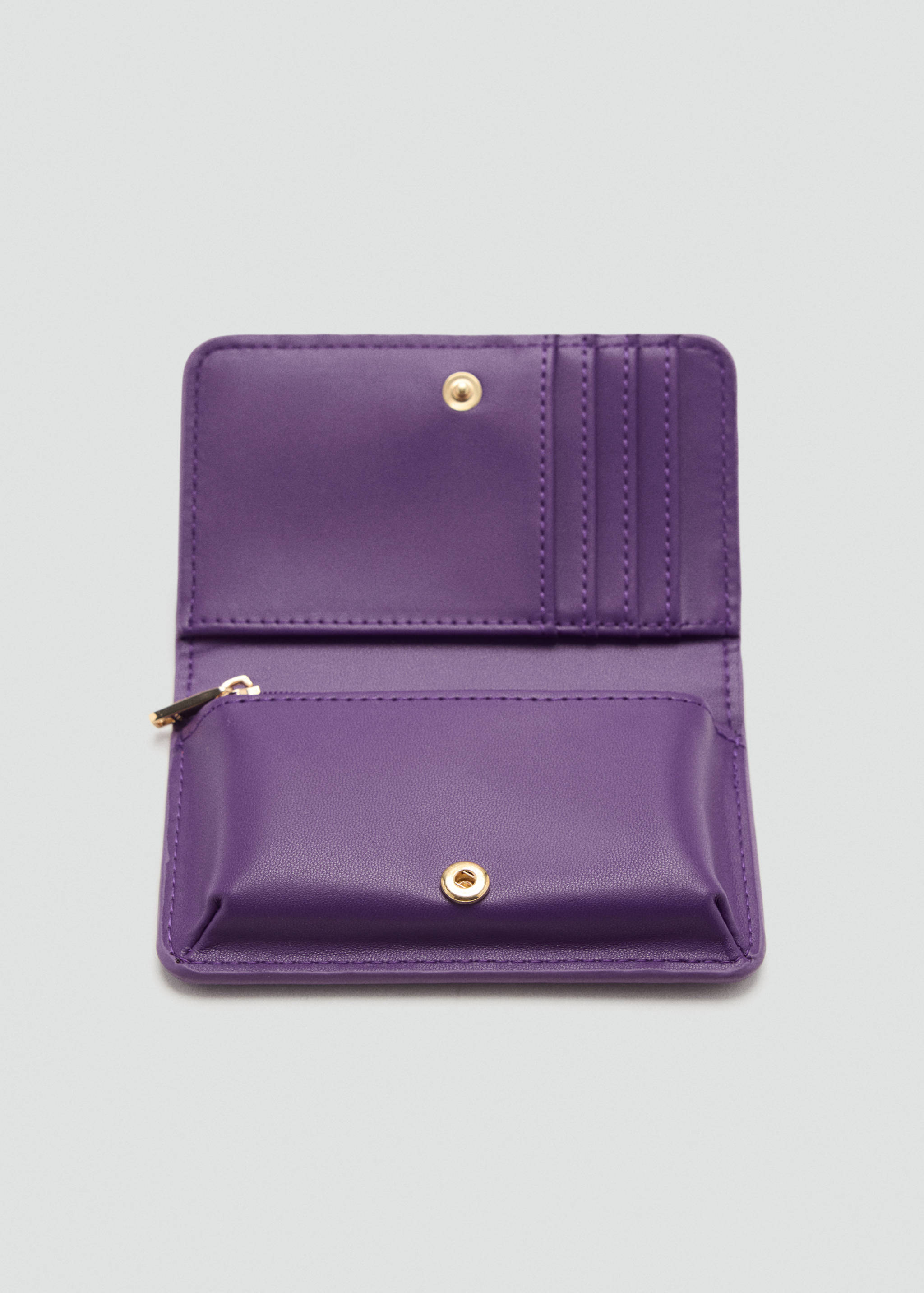 Close-up of an open purple wallet with card slots and gold-toned hardware.