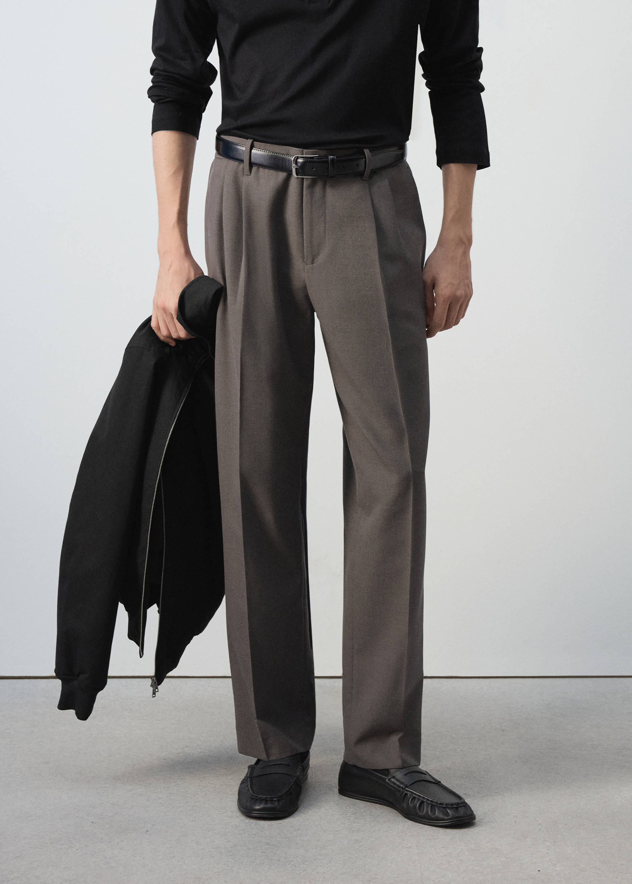 Dark brown pleated straight-leg trousers worn with a black belt.