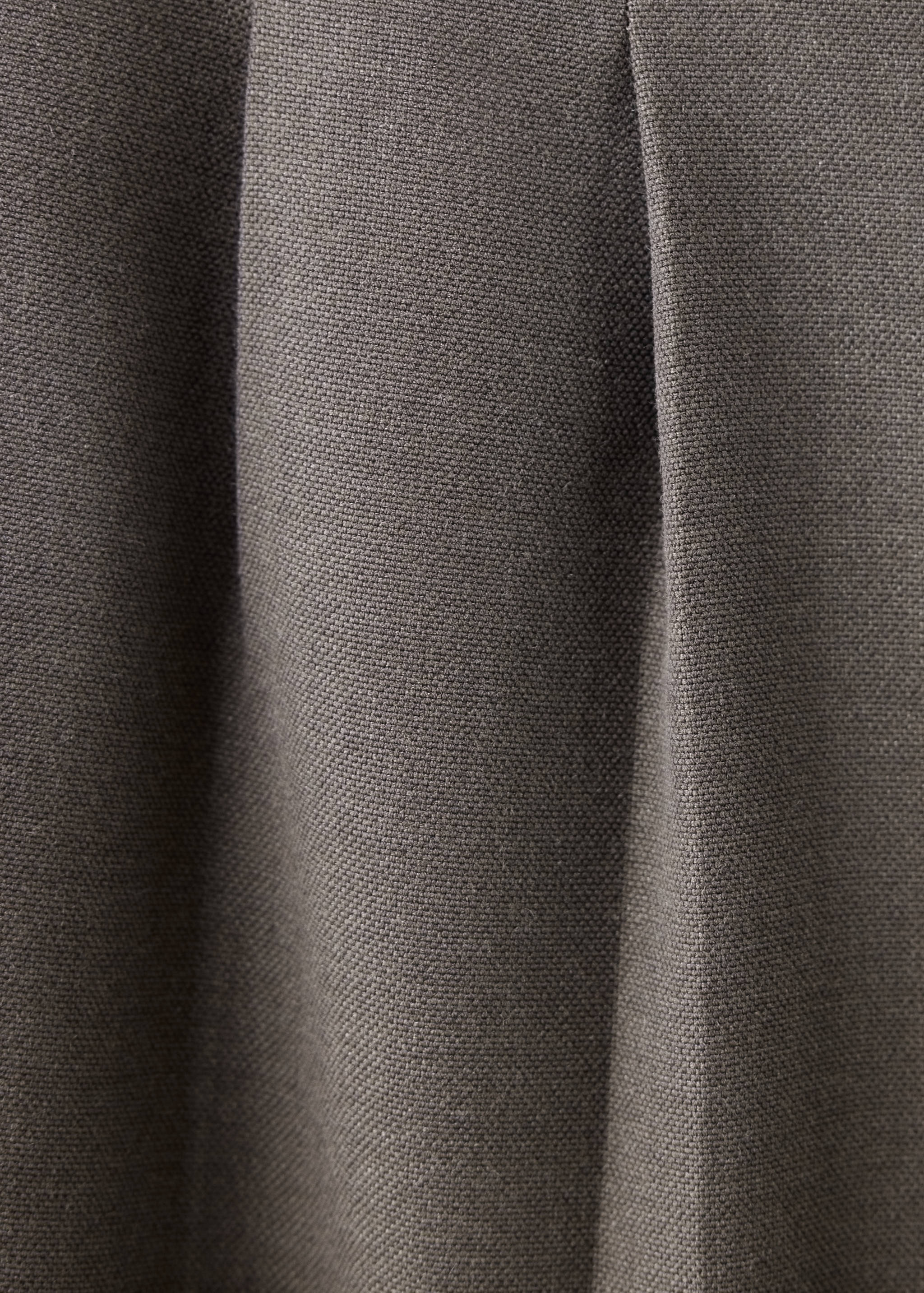 Grey trousers fabric and pleat detail.
