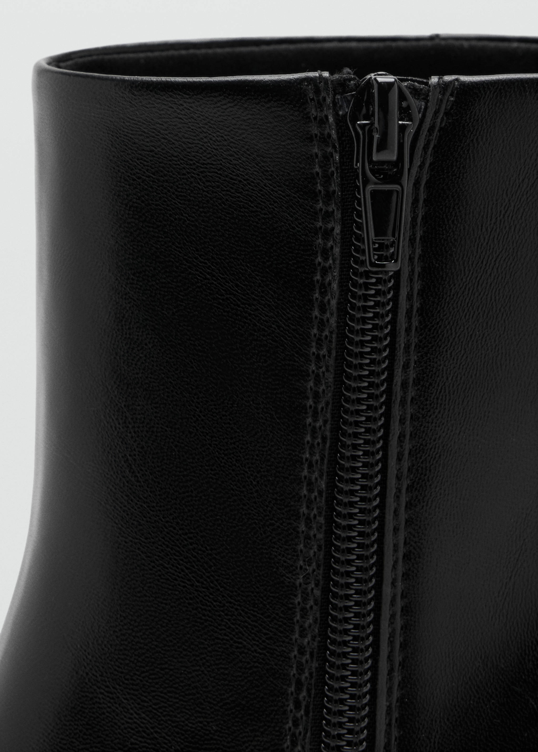 Close-up of the side zip detail on a black leather ankle boot.