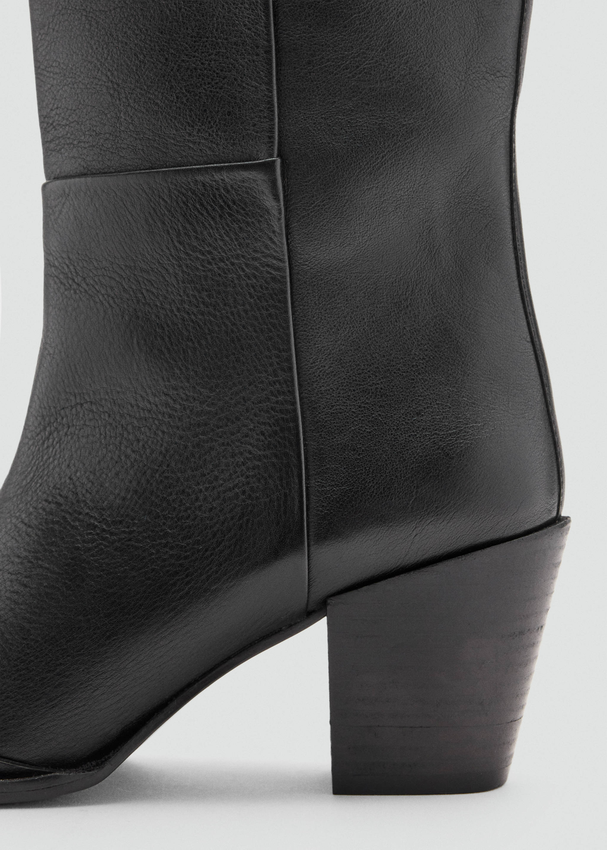 Close-up of a black leather boot showing the textured material and chunky block heel.