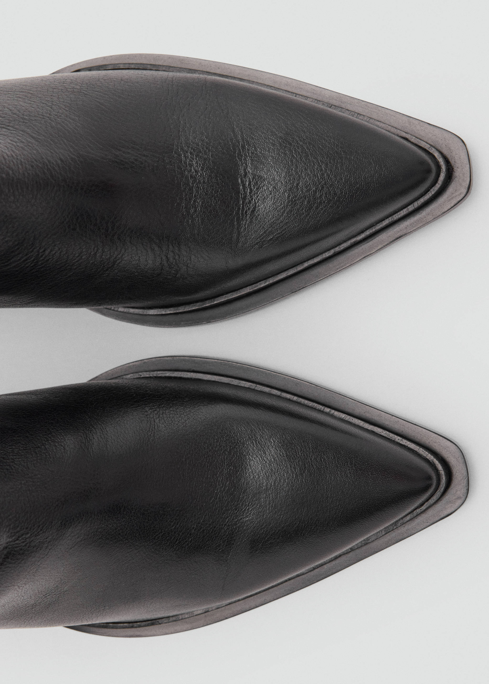 Close-up of black leather boots with a pointed toe.