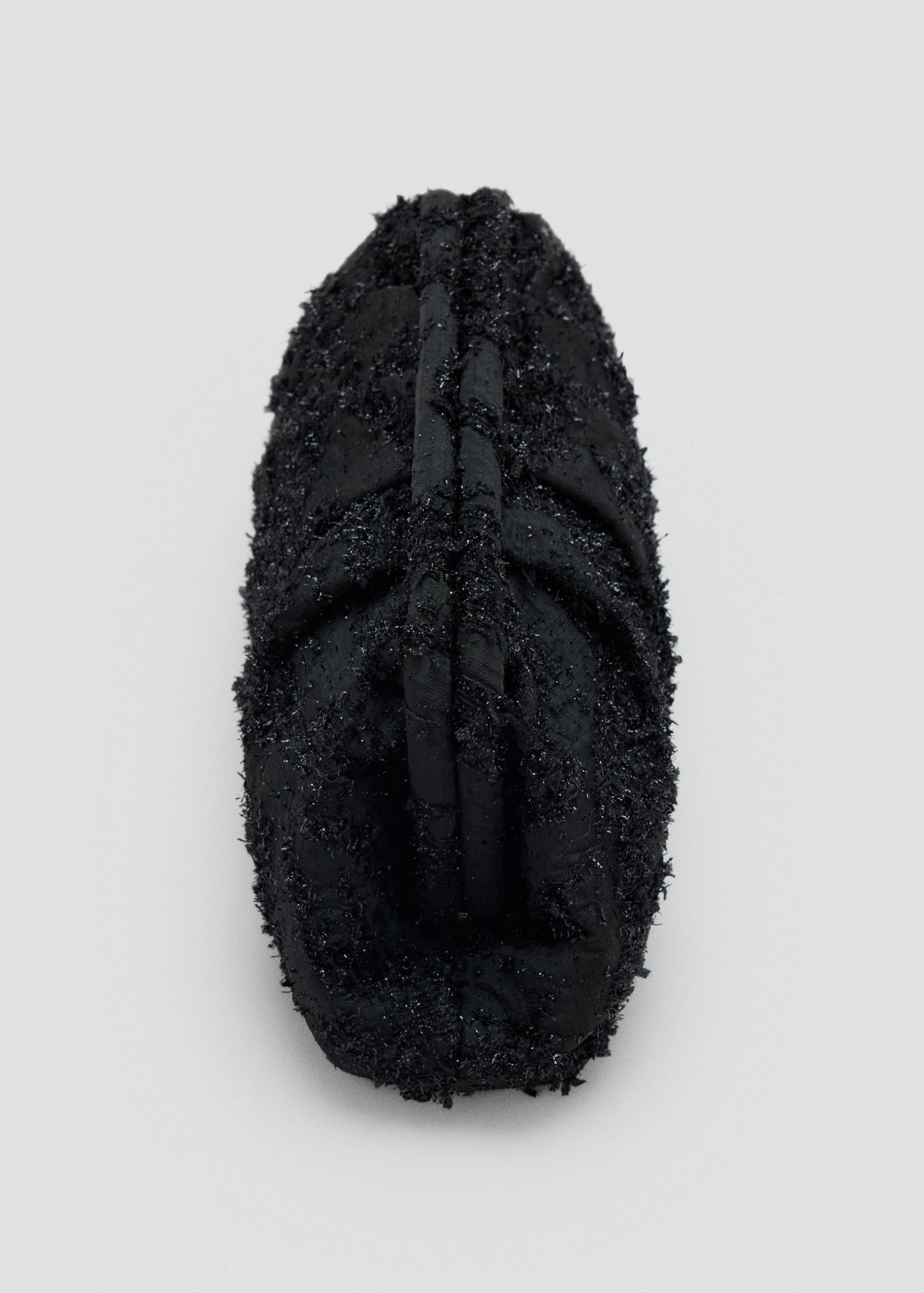 Close-up of a black textured handbag with top handles.