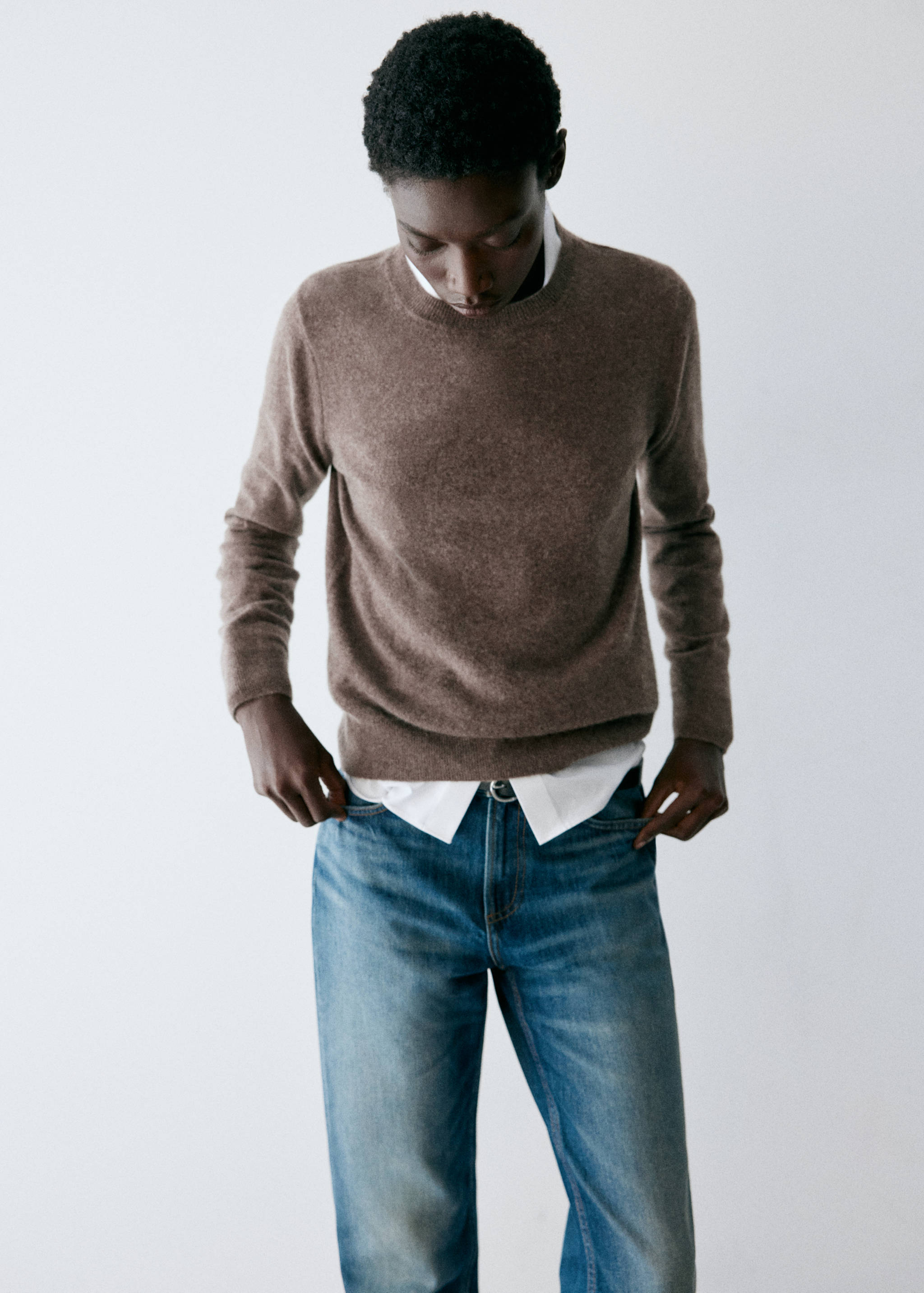 Brown knit jersey with a round neckline layered over a white shirt.