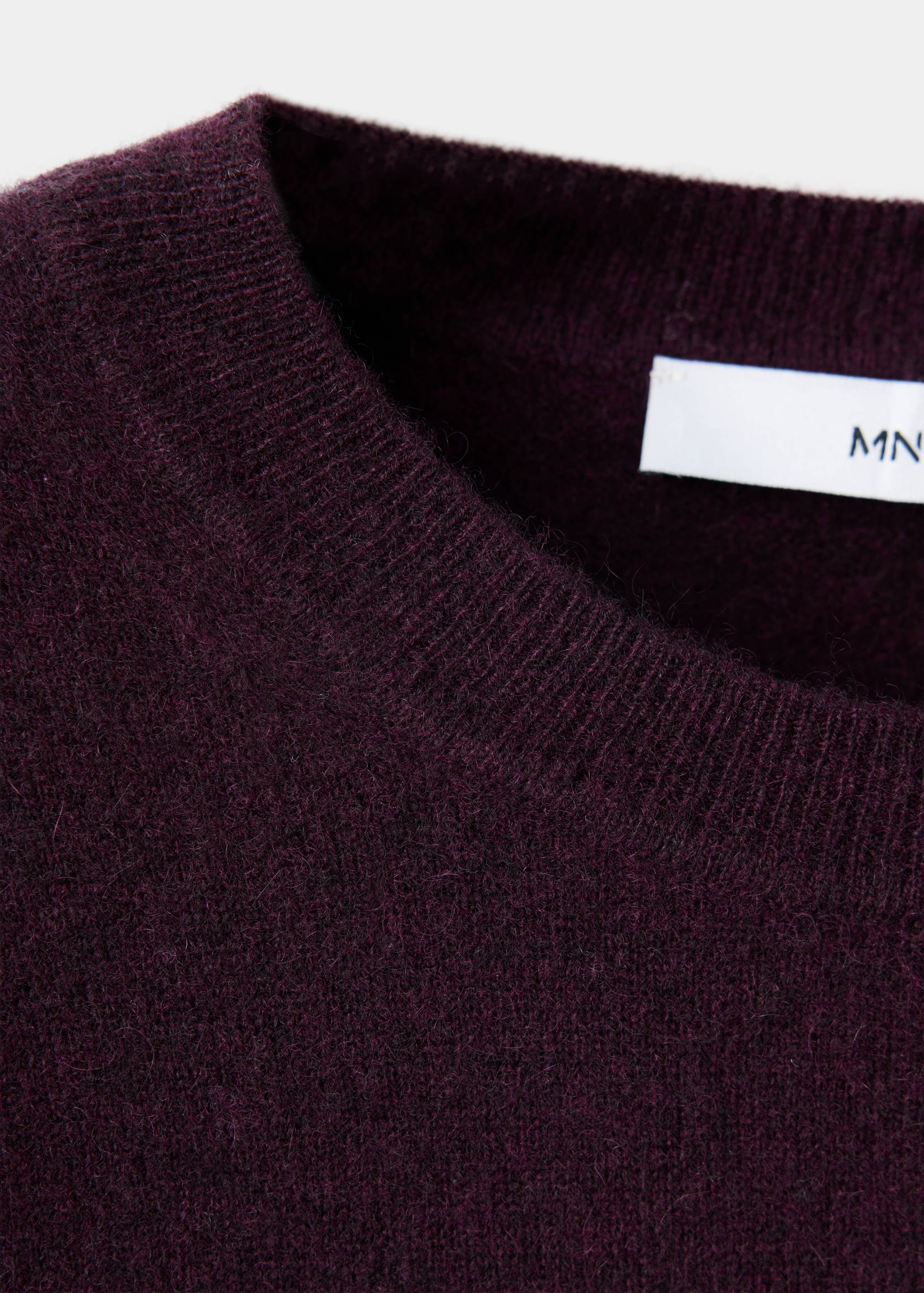Close-up of a plum jumper featuring a ribbed crew neckline.