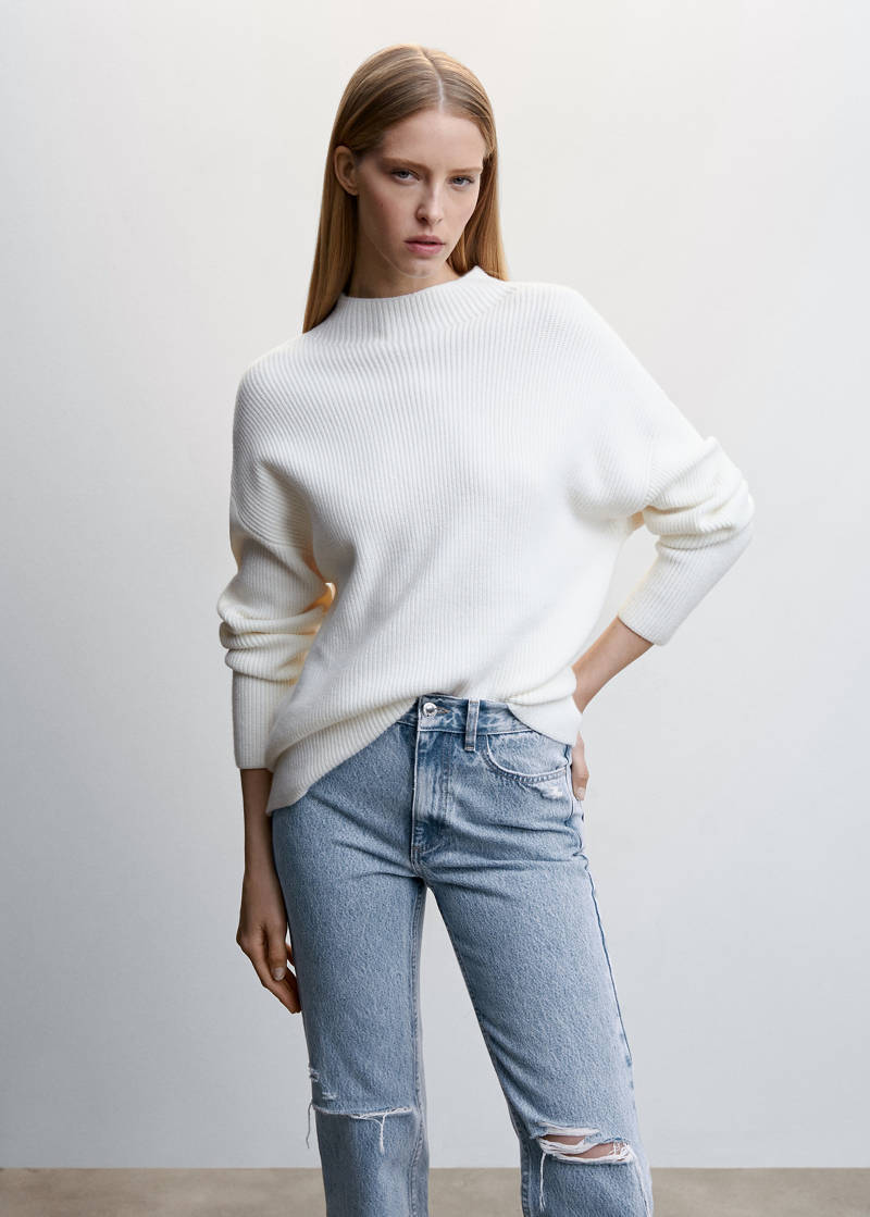 Woman in cream turtleneck sweater with blue jeans