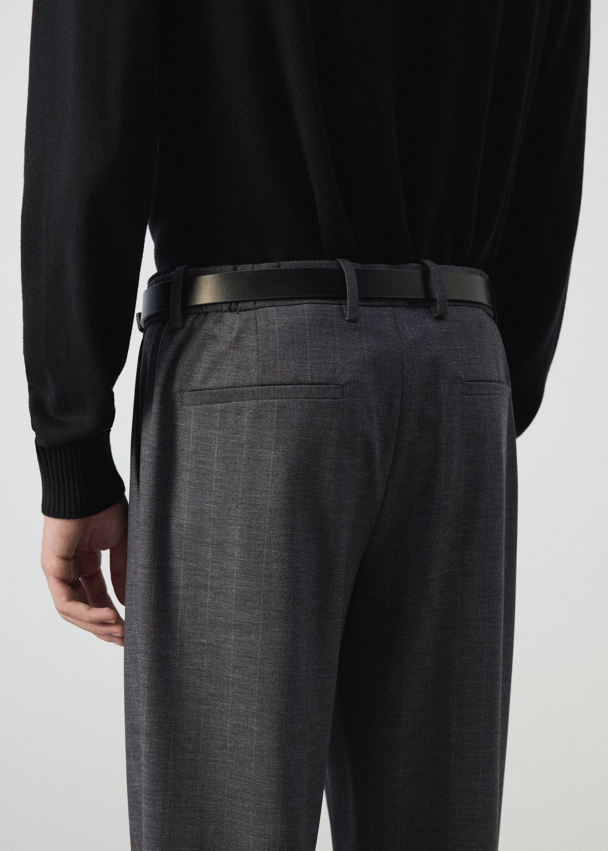 Pantalones grises de raya diplomática vistos desde atrás, combinados con un cinturón negro