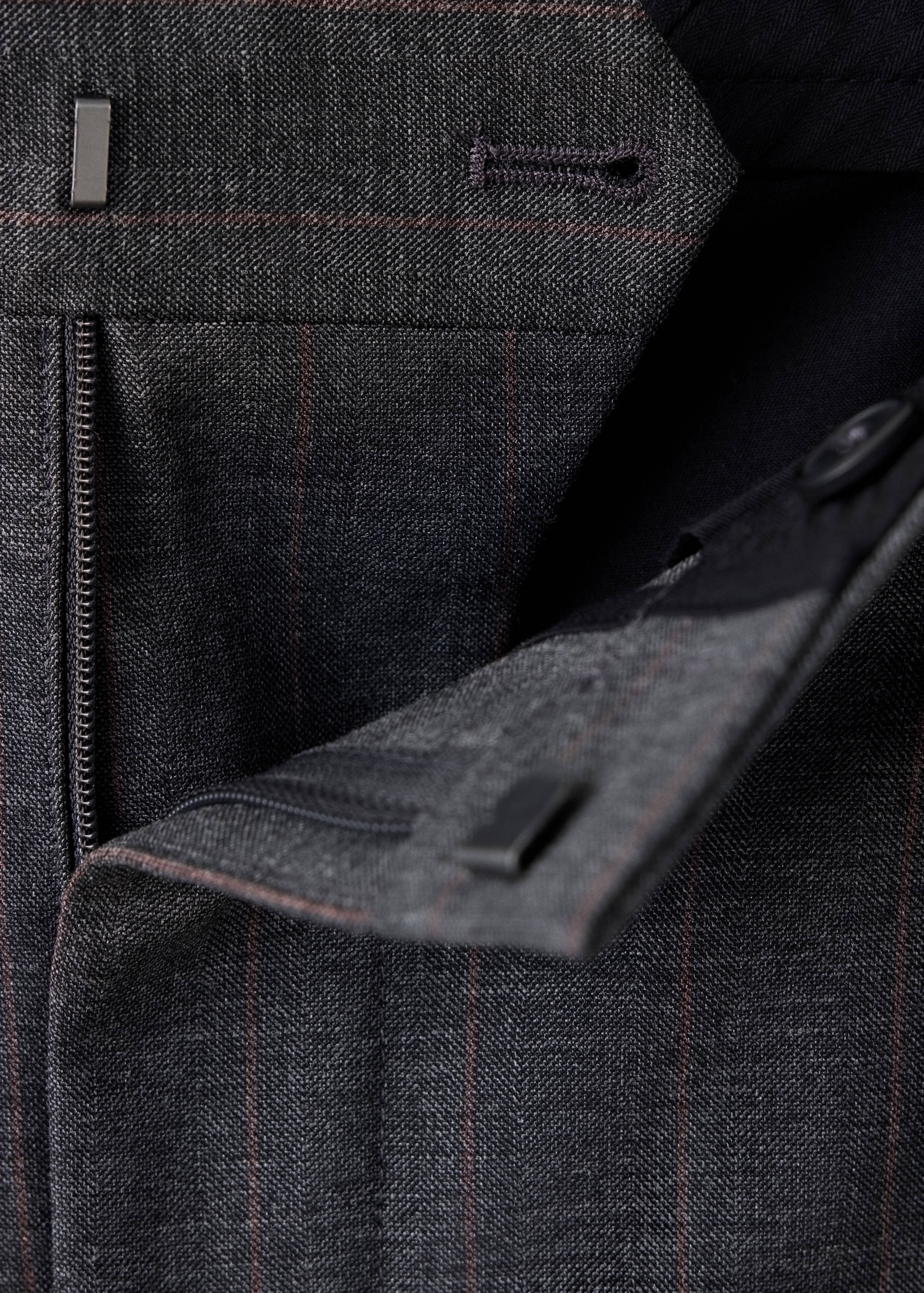Detalle de la cinturilla sastre y el cierre en pantalón gris oscuro estampado.