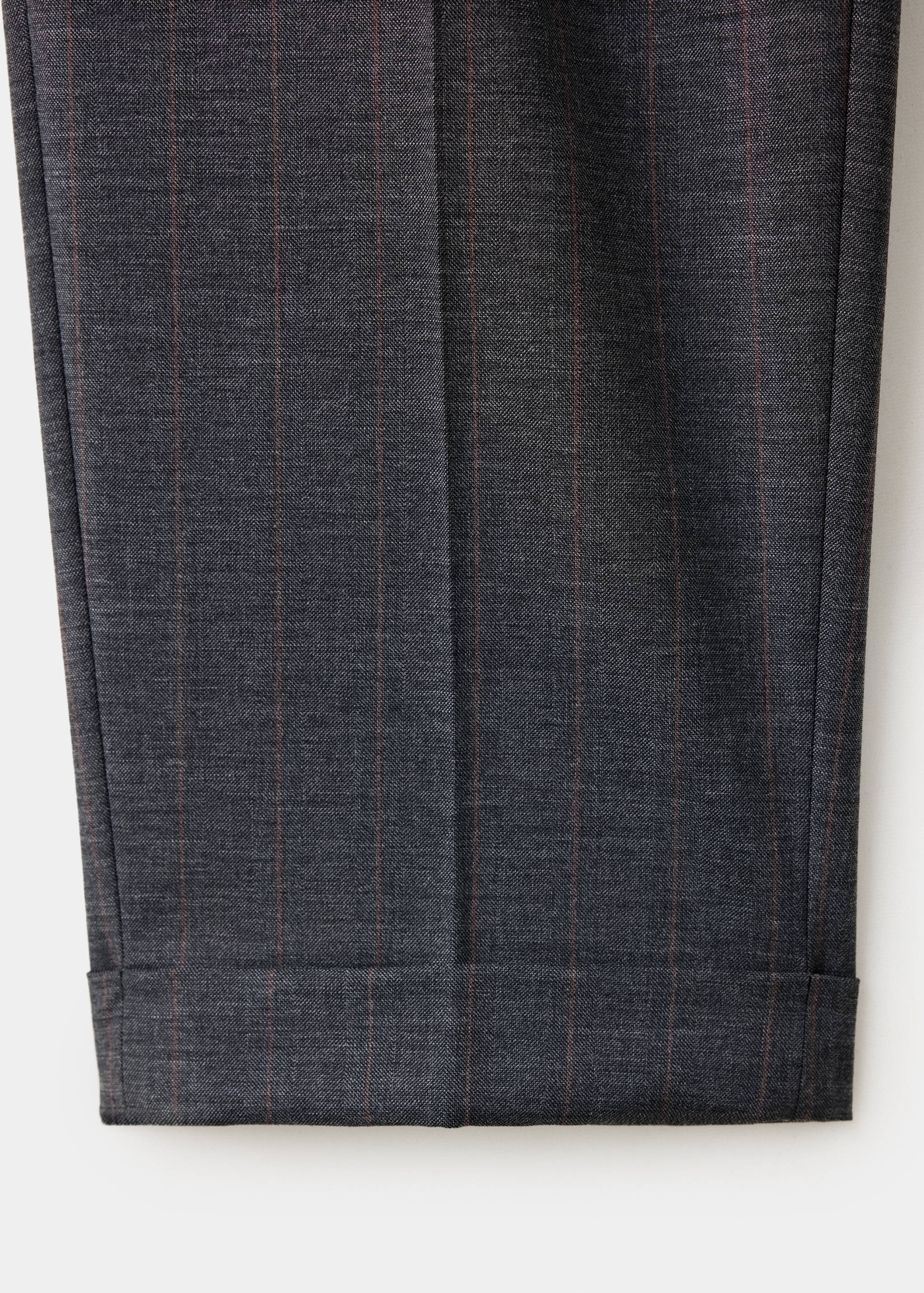 Detalle de pantalón gris oscuro de rayas diplomáticas con raya marcada.