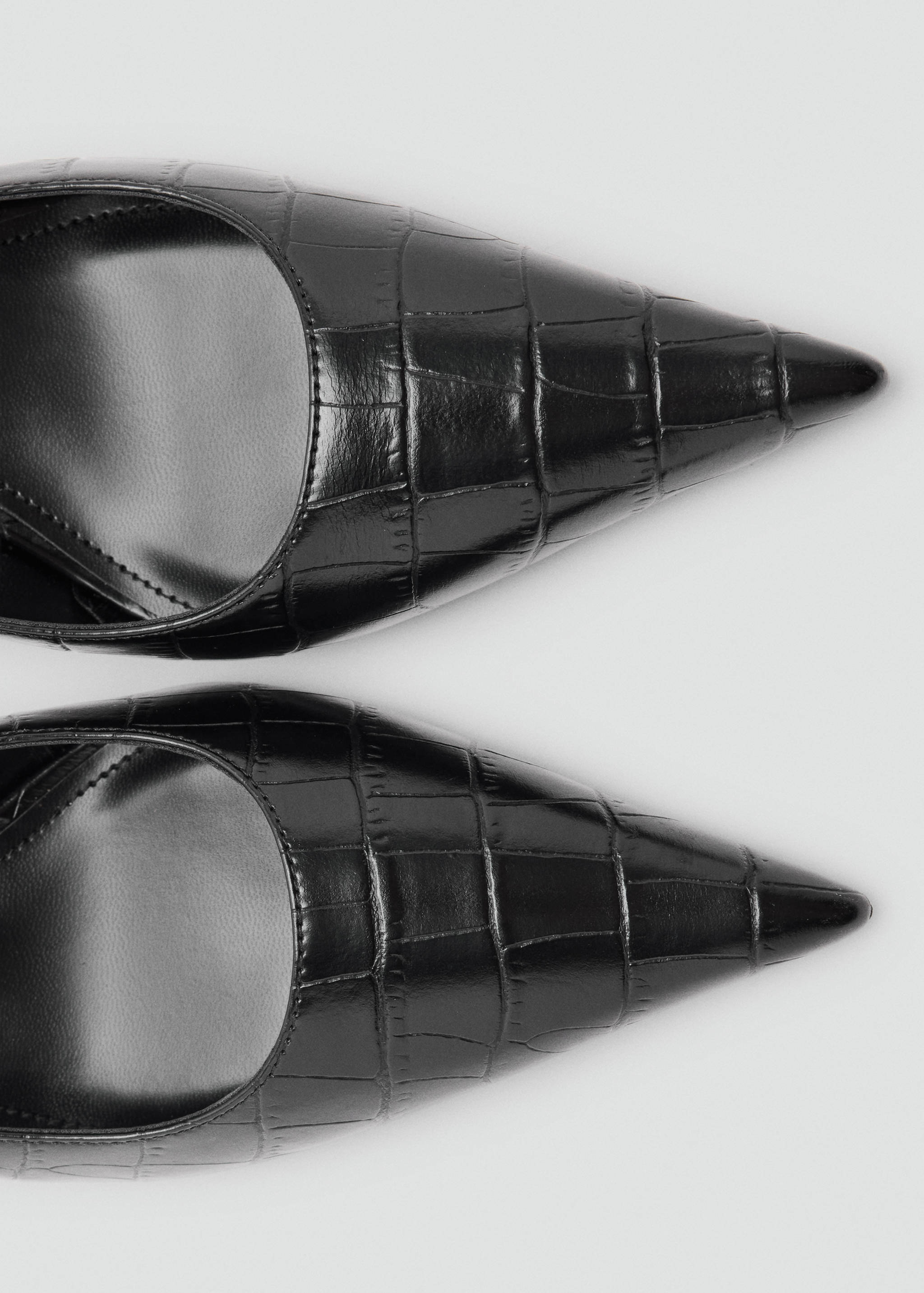 Close-up of black crocodile-embossed pointed shoes.