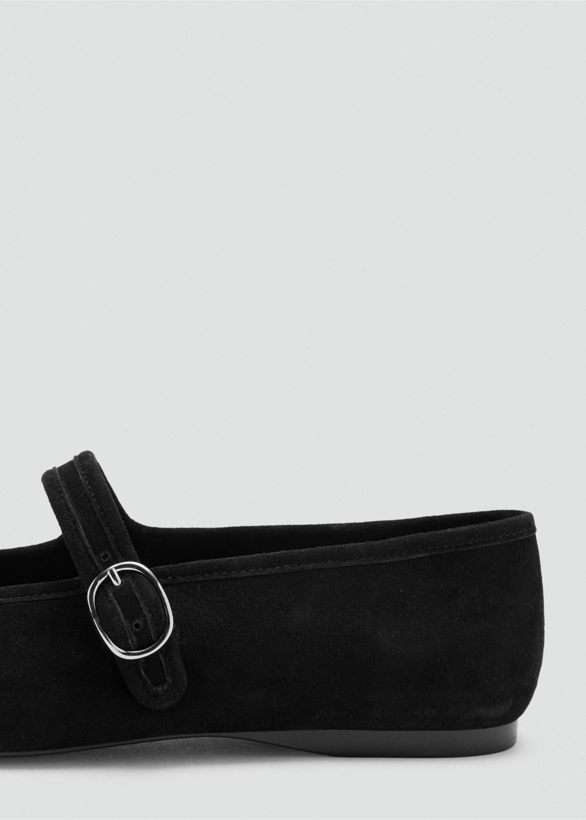 Close-up of a black shoe featuring a strap with a round buckle., Black. Ref: 47041335-00.
