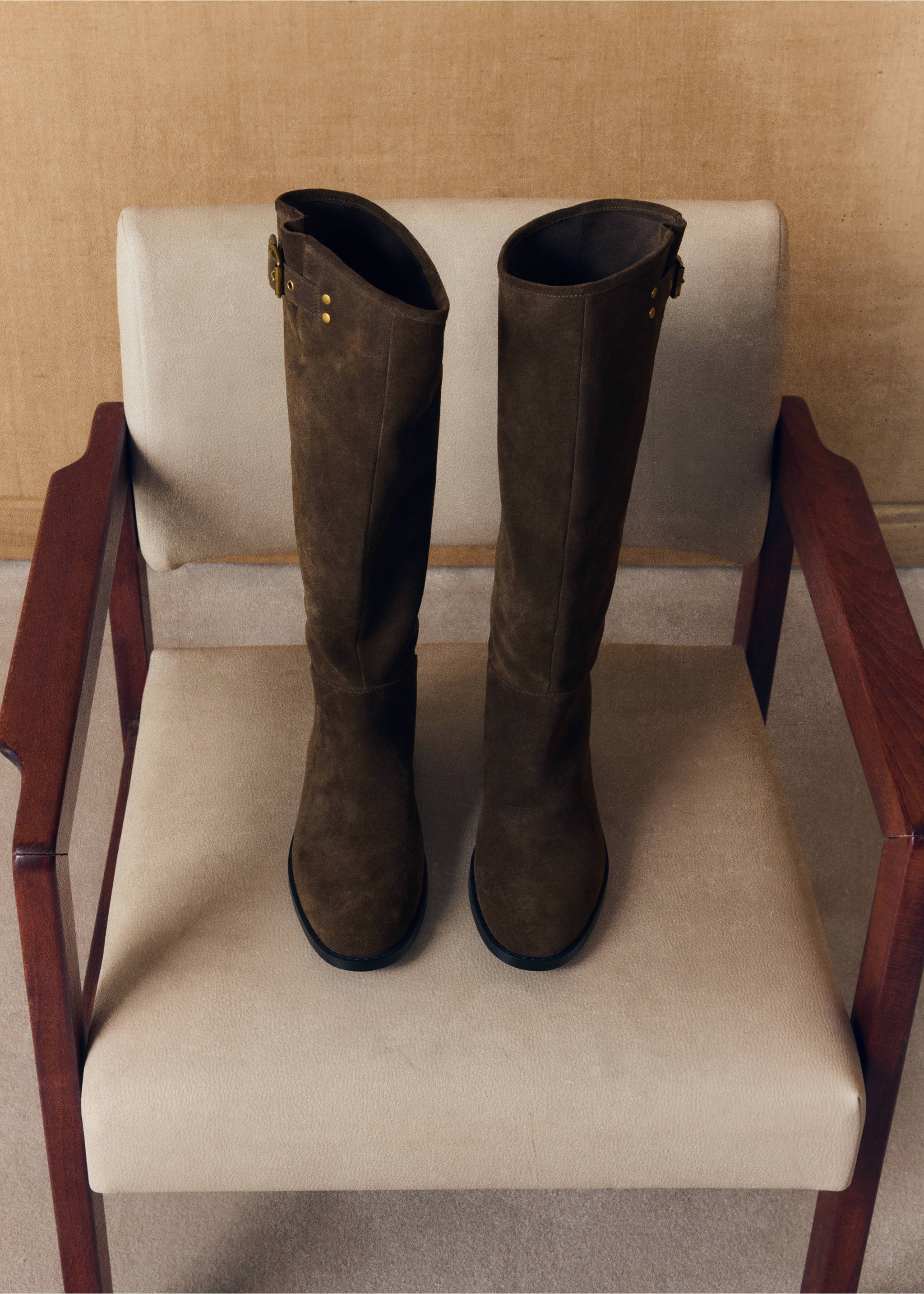 Dark brown suede knee-high boots with buckle and stud details on an armchair., Medium Brown. Ref: 47041337-00.