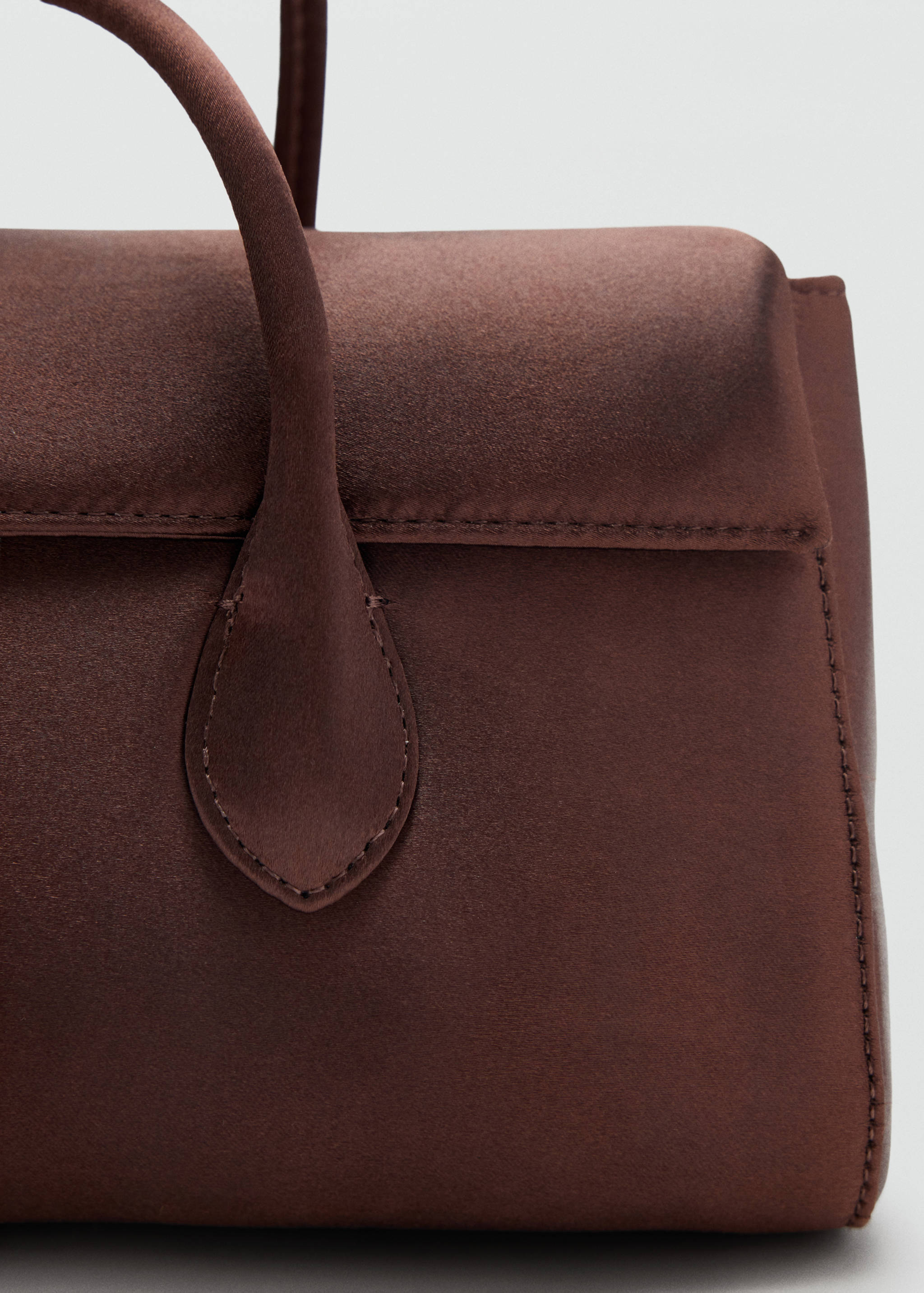 Brown shoulder bag detail showing the flap and handle.
