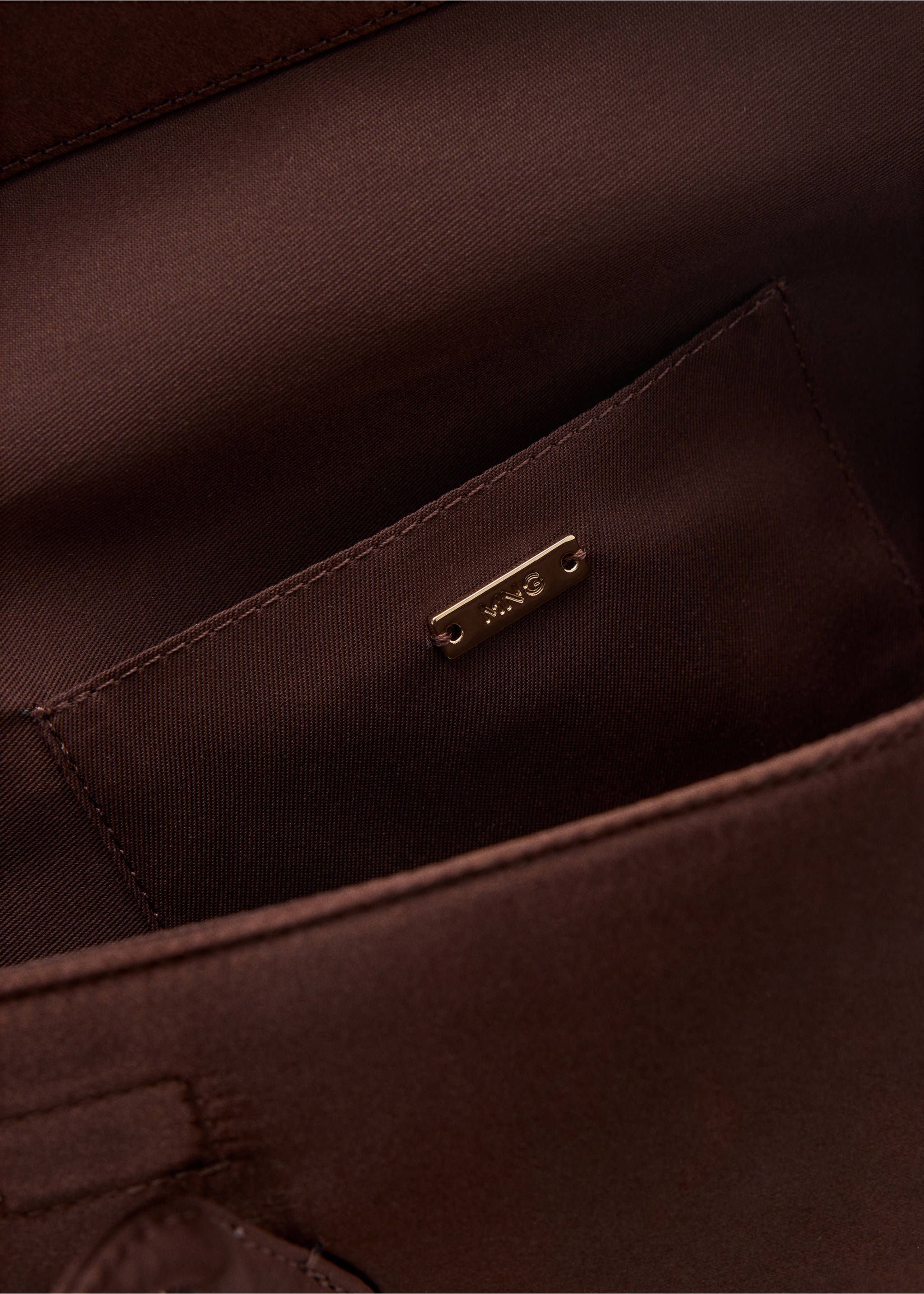 Close-up of the dark brown shoulder bag interior pocket with a gold MNG plaque., Brown. Ref: 47041346-00.