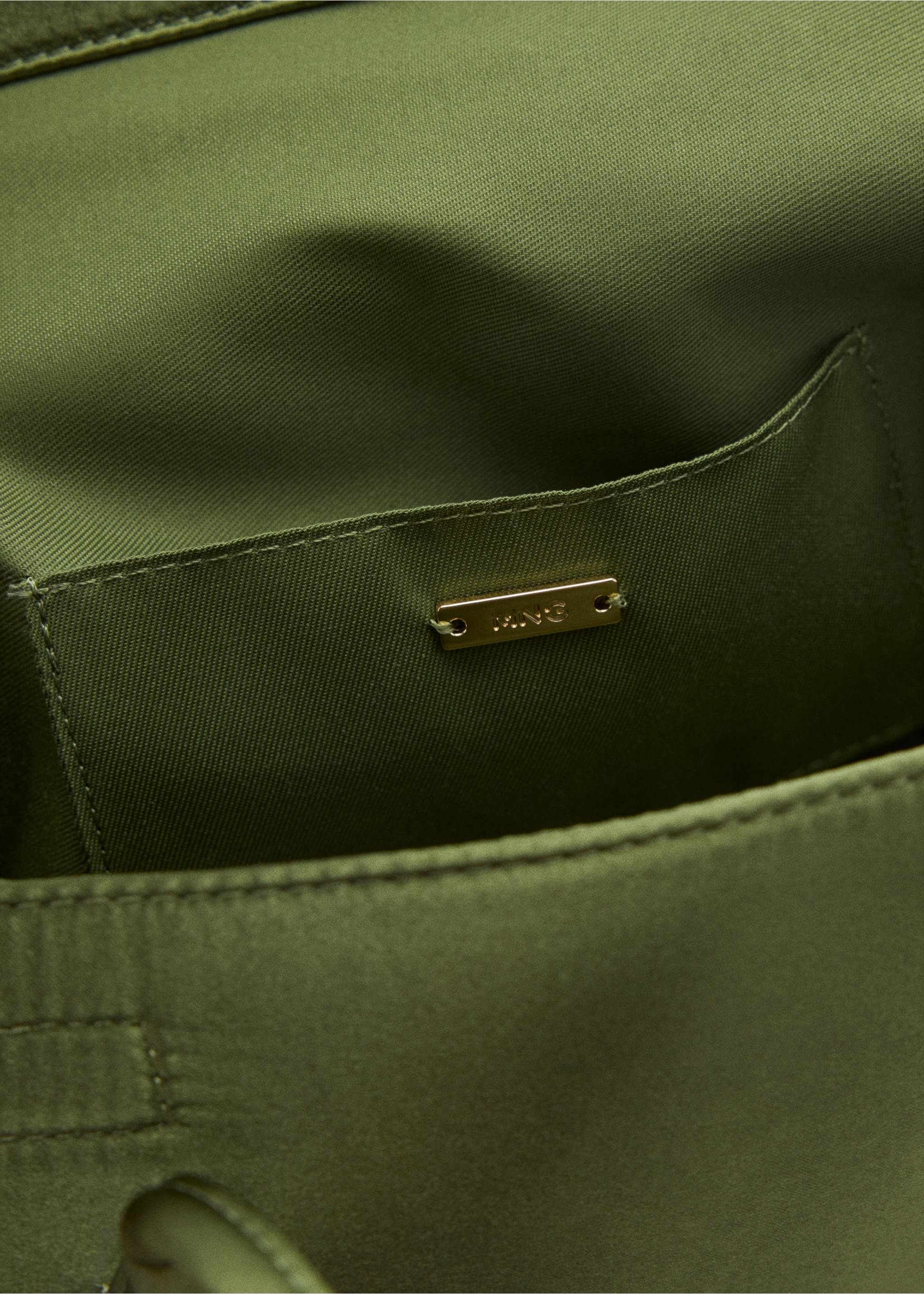 Close-up of an olive green shoulder bag interior showing the pocket and gold brand plaque., Green. Ref: 47041346-00.
