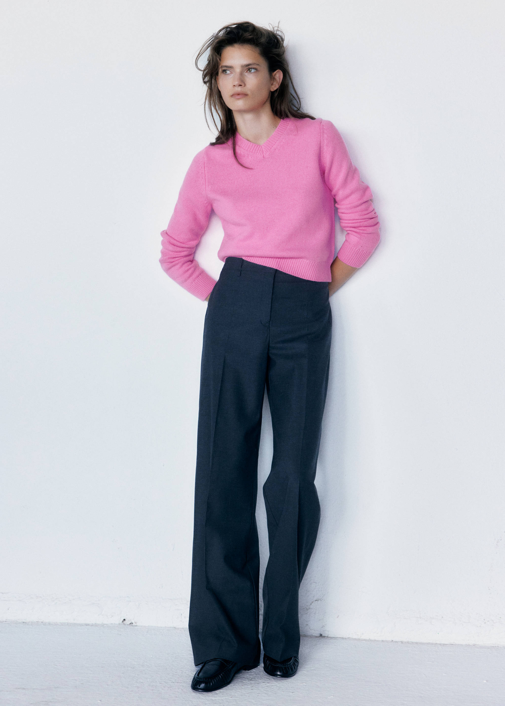 Bright pink V-neck jersey worn with dark grey wide-leg trousers.