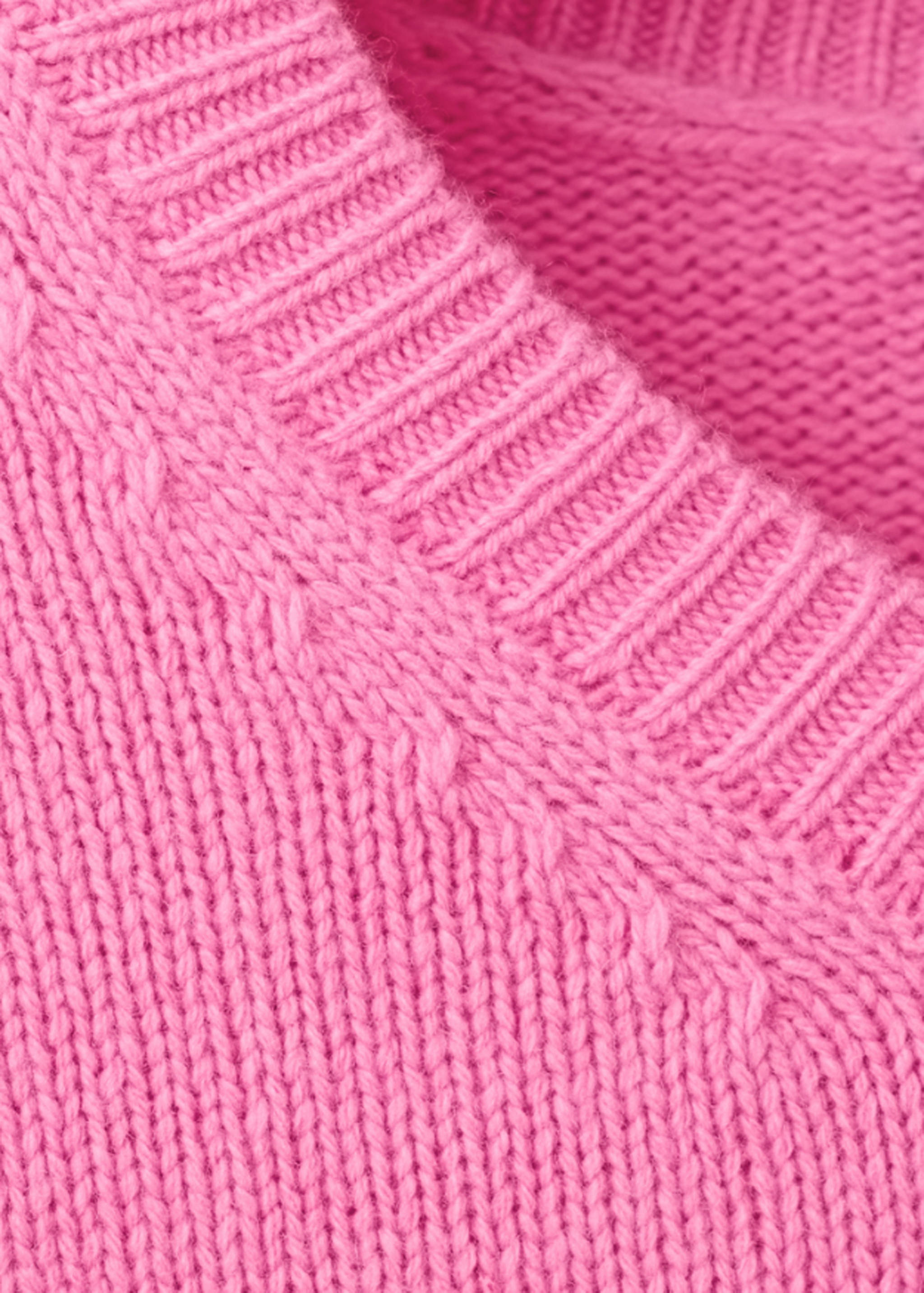 Close-up of a pink knit jumper showing the ribbed collar detail.