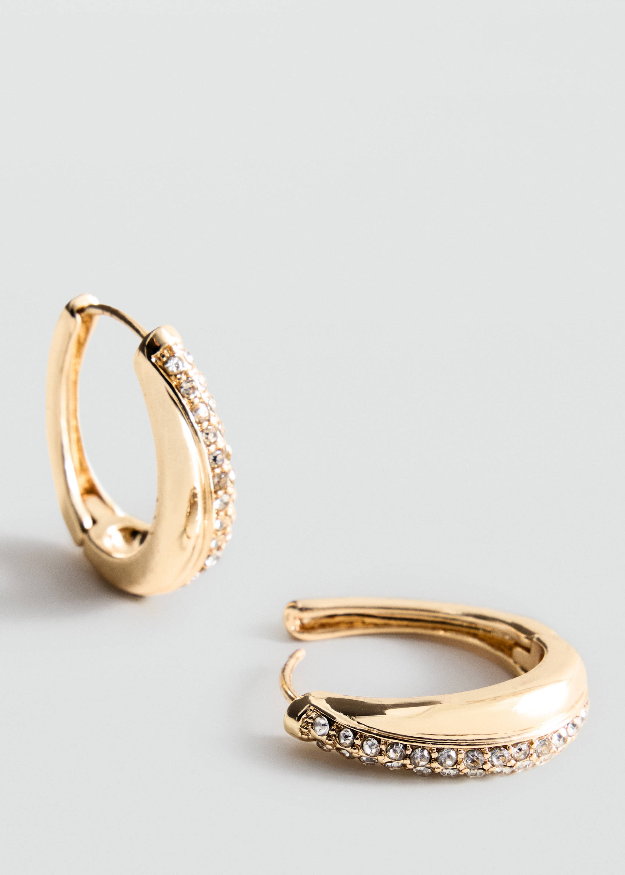 Gold hoop earrings with pavé crystal details.