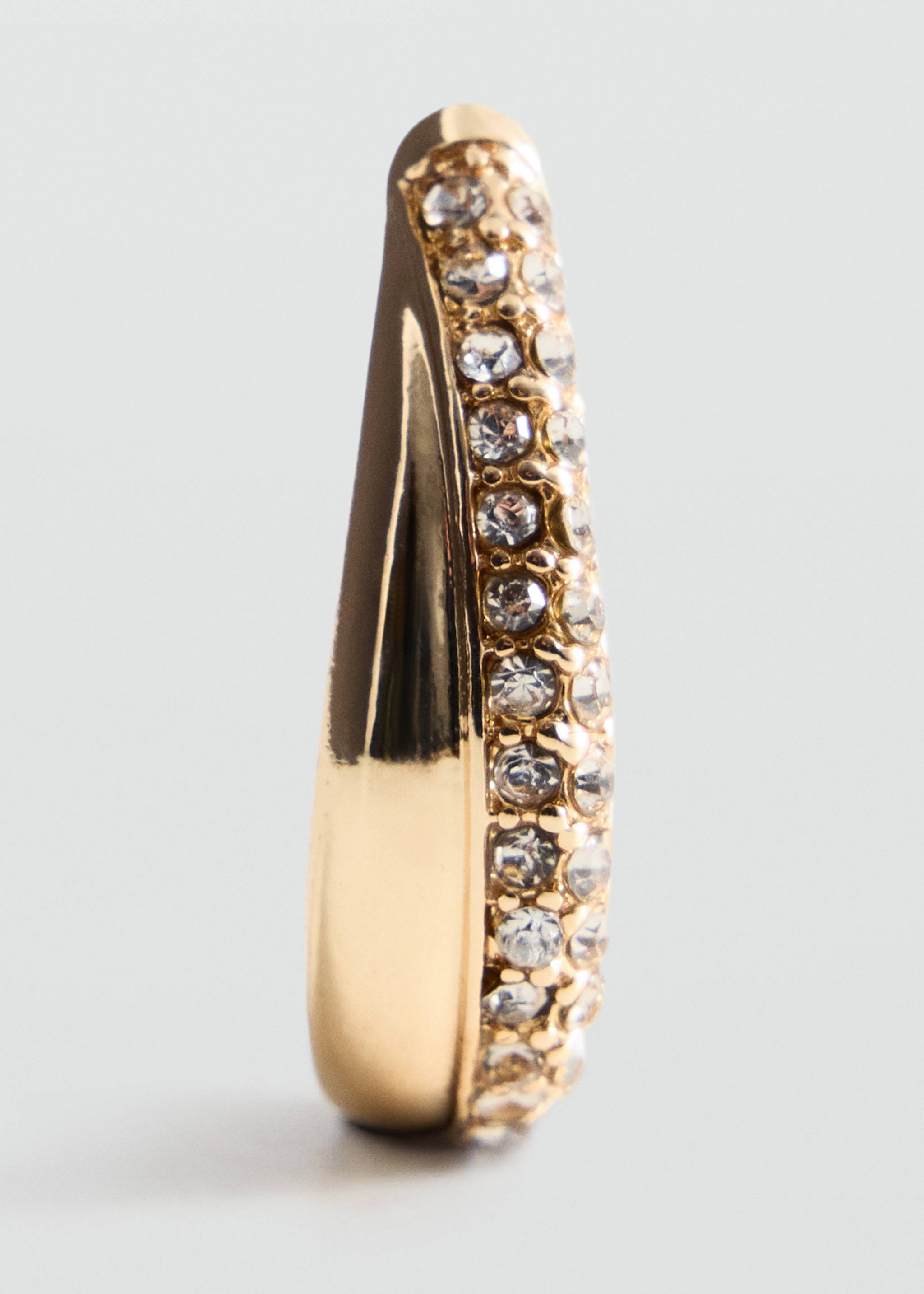 Close-up of a gold-tone earring with crystal rhinestones.