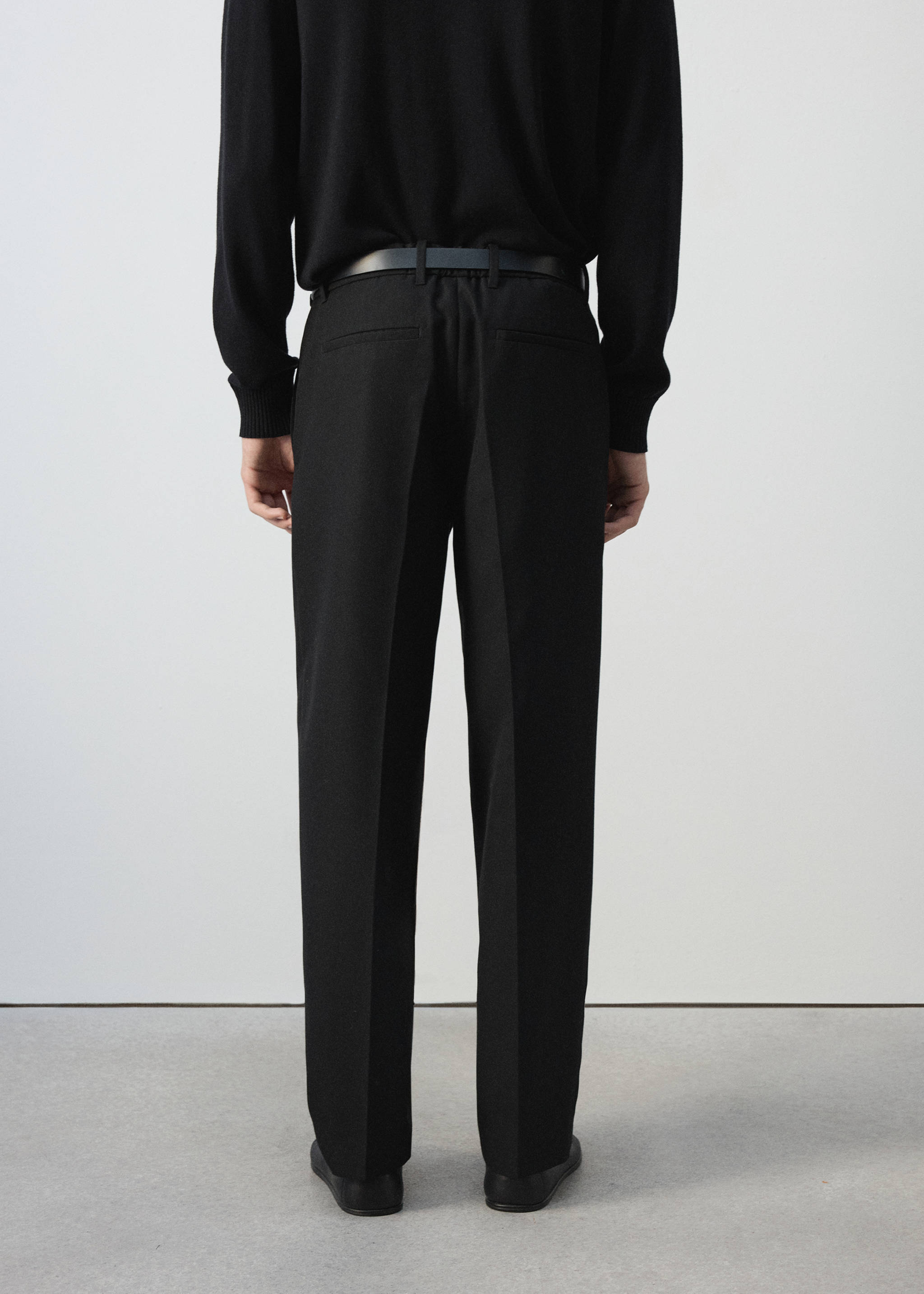 Vista trasera de pantalones negros con raya marcada y trabillas.