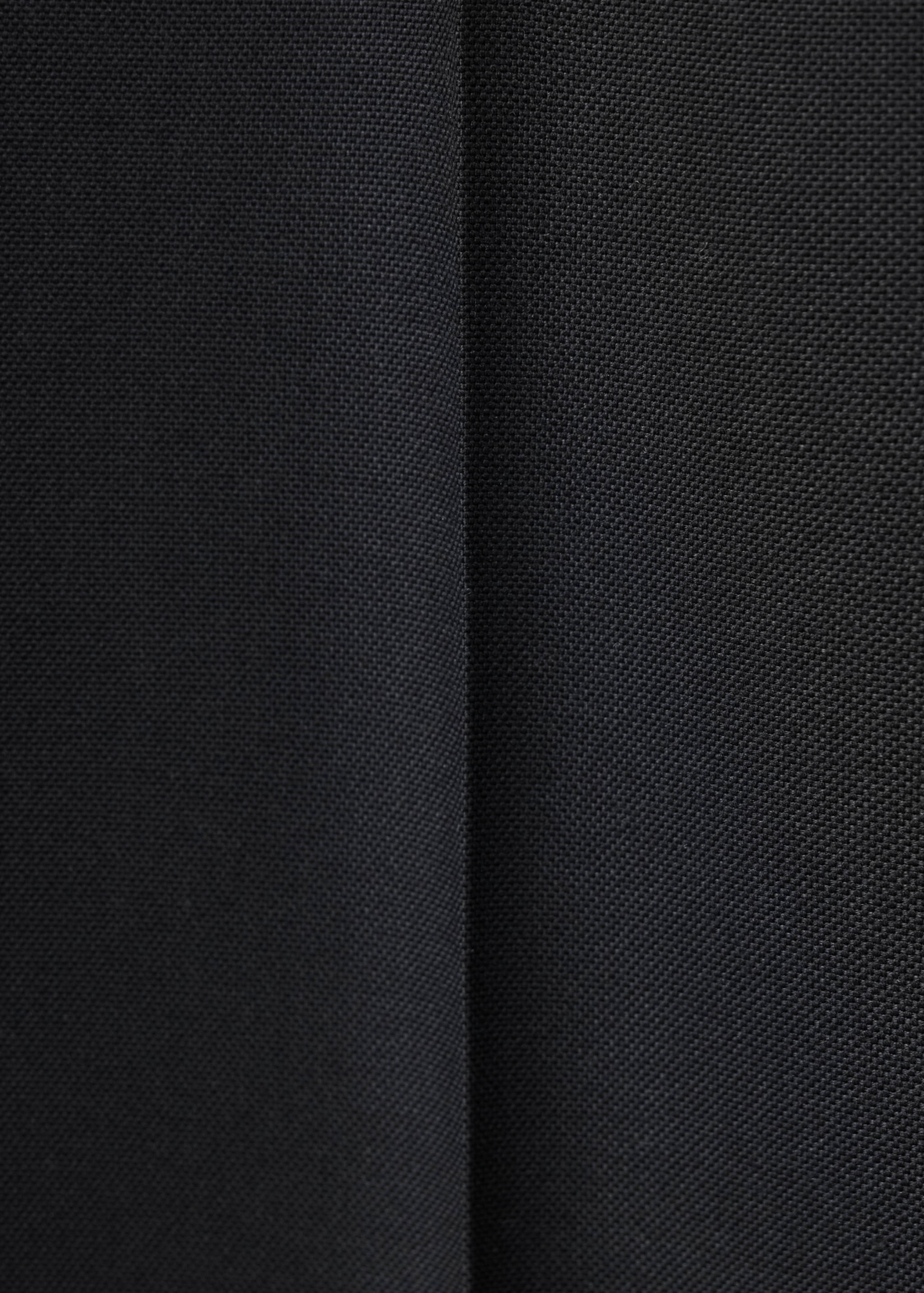 Primer plano de pantalón negro con tejido texturizado y detalle de costuras.