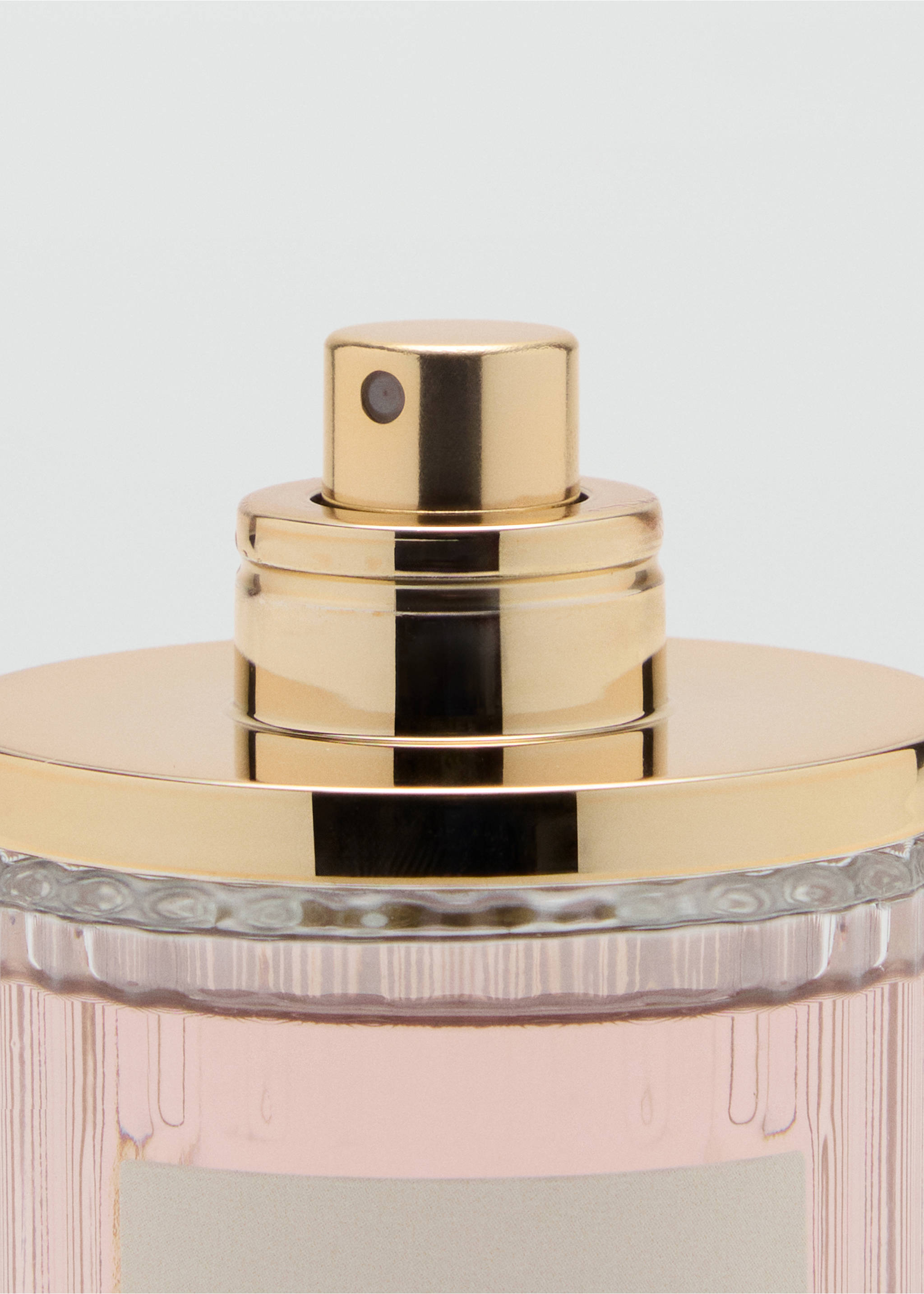 Close-up of a perfume bottle with a metallic gold cap and a pale pink glass body., Mink Grey. Ref: 47051334-00.