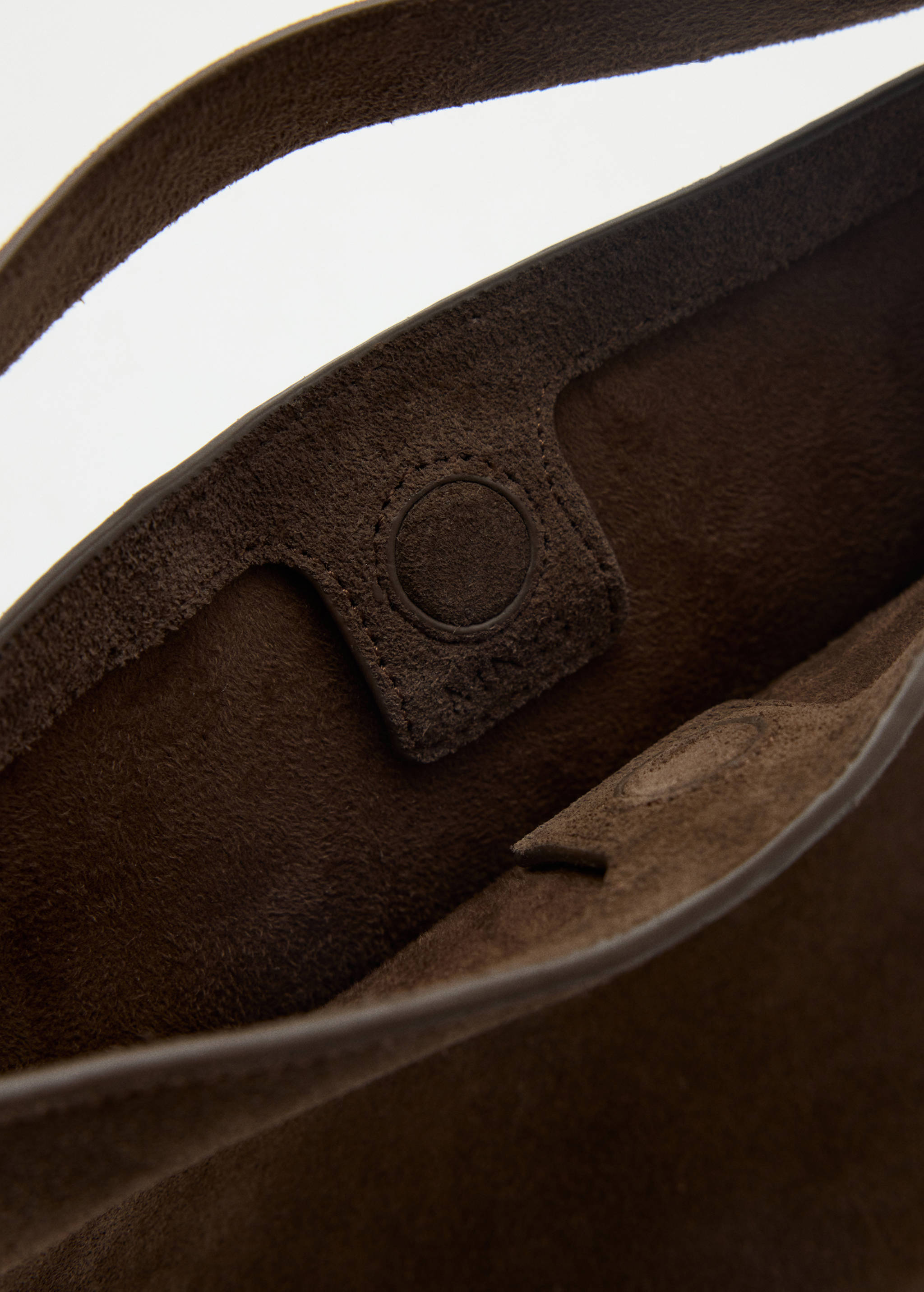 Close-up of the interior and magnetic closure of a brown suede bucket bag.