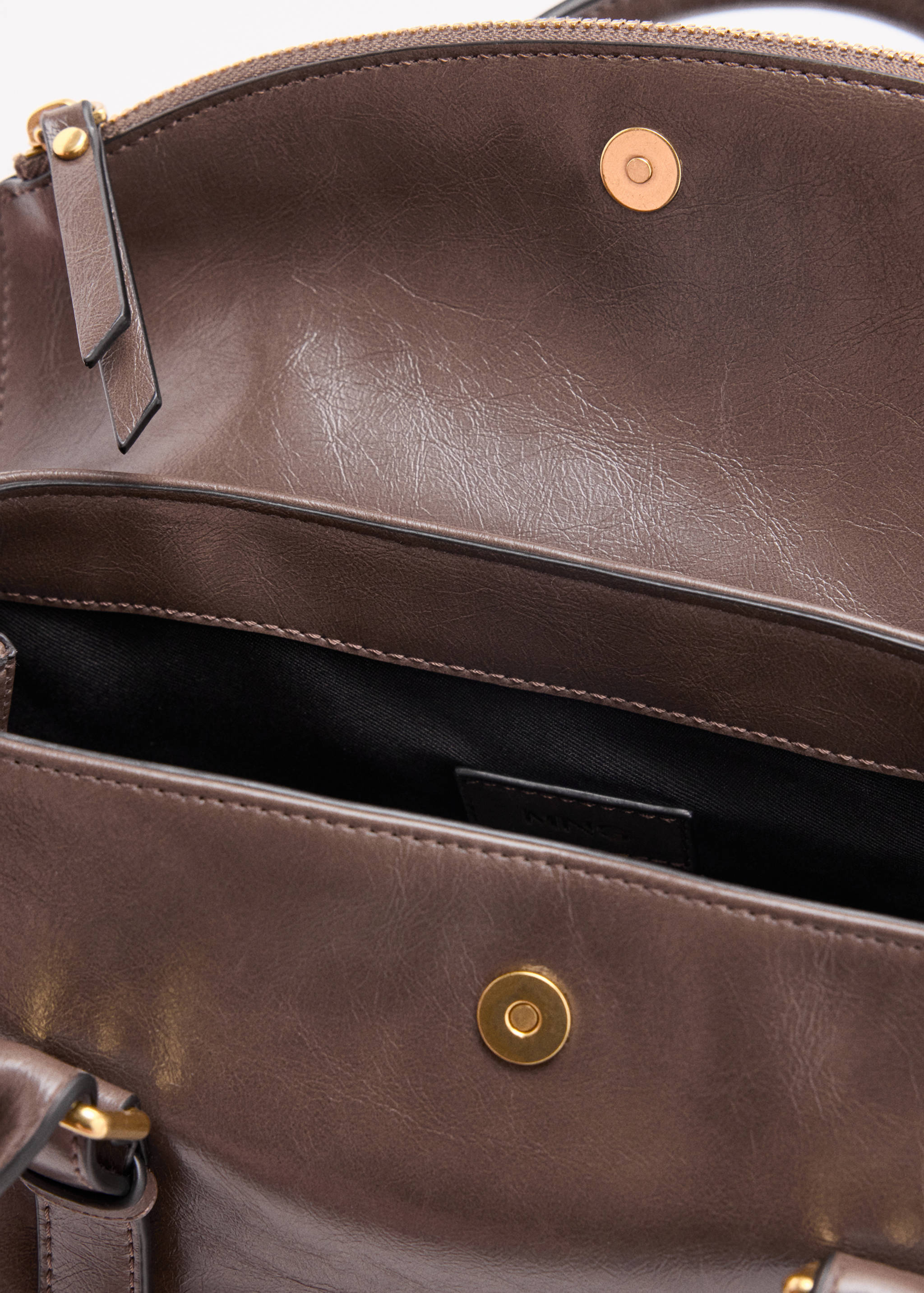 Close-up of a brown city bag interior and magnetic snap closure.