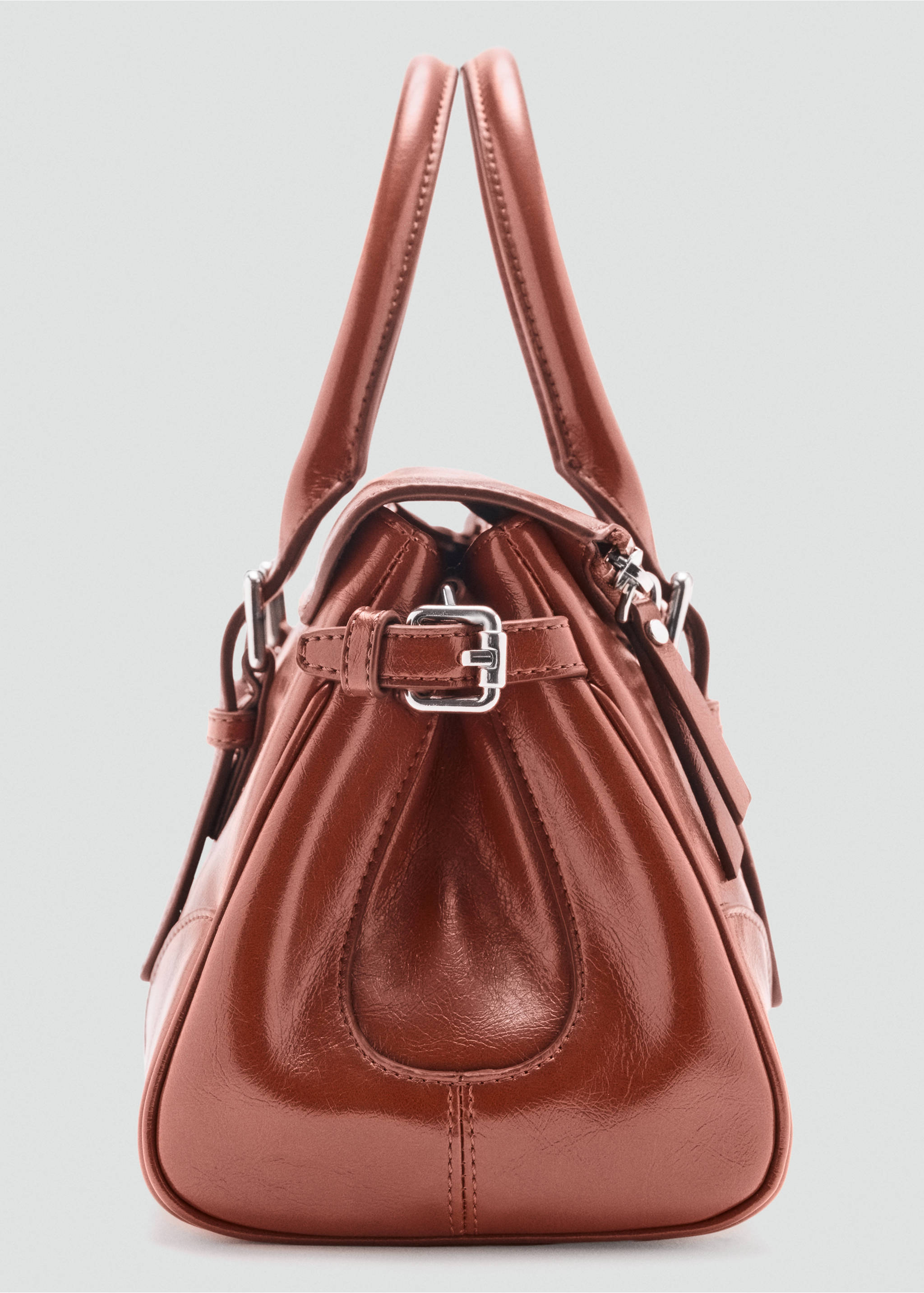 Close-up of a brown city bag showing the side profile, handles, and silver buckle detail., Cognac. Ref: 47051345-00.