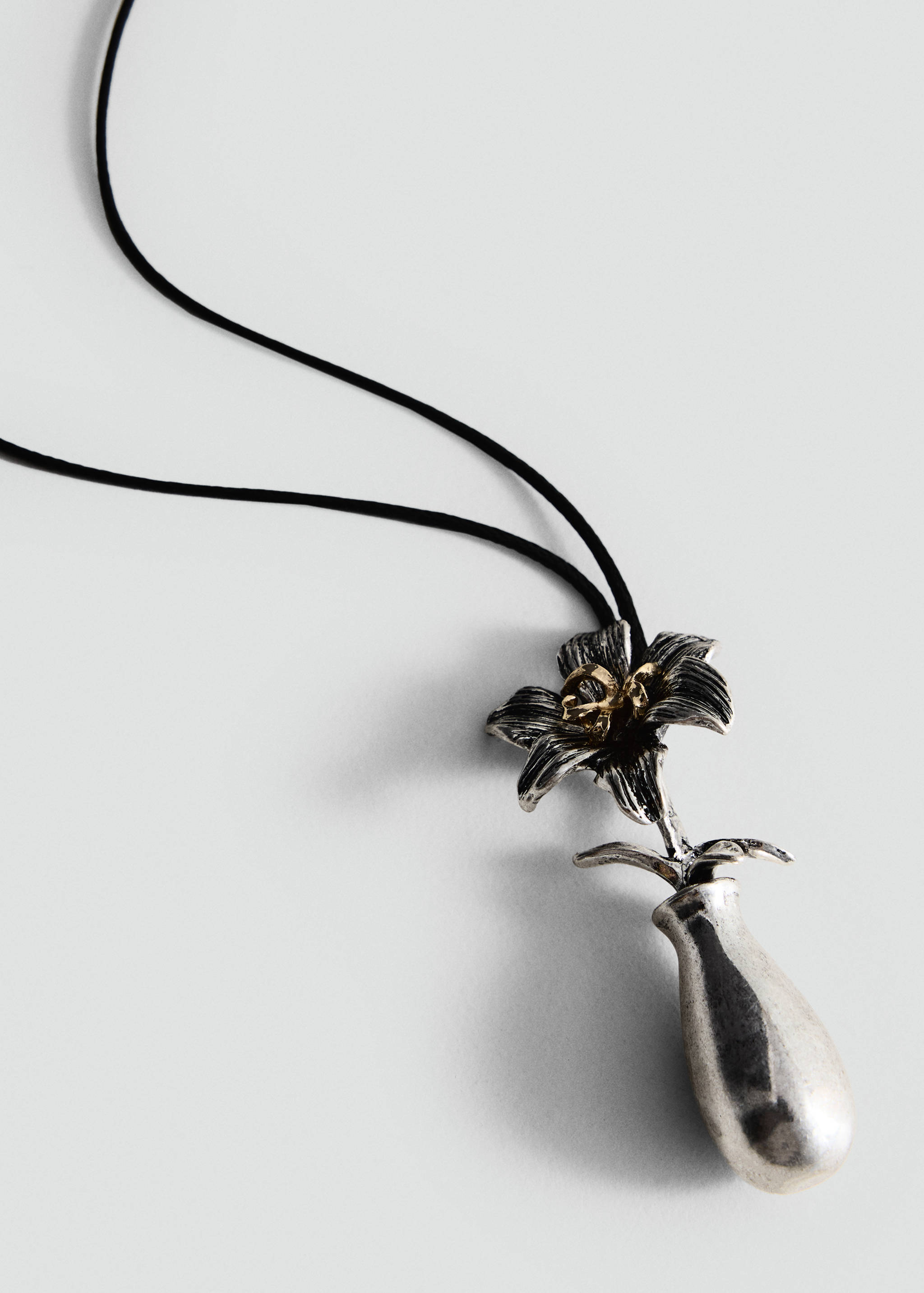 Silver flower pendant necklace on a thin black cord.