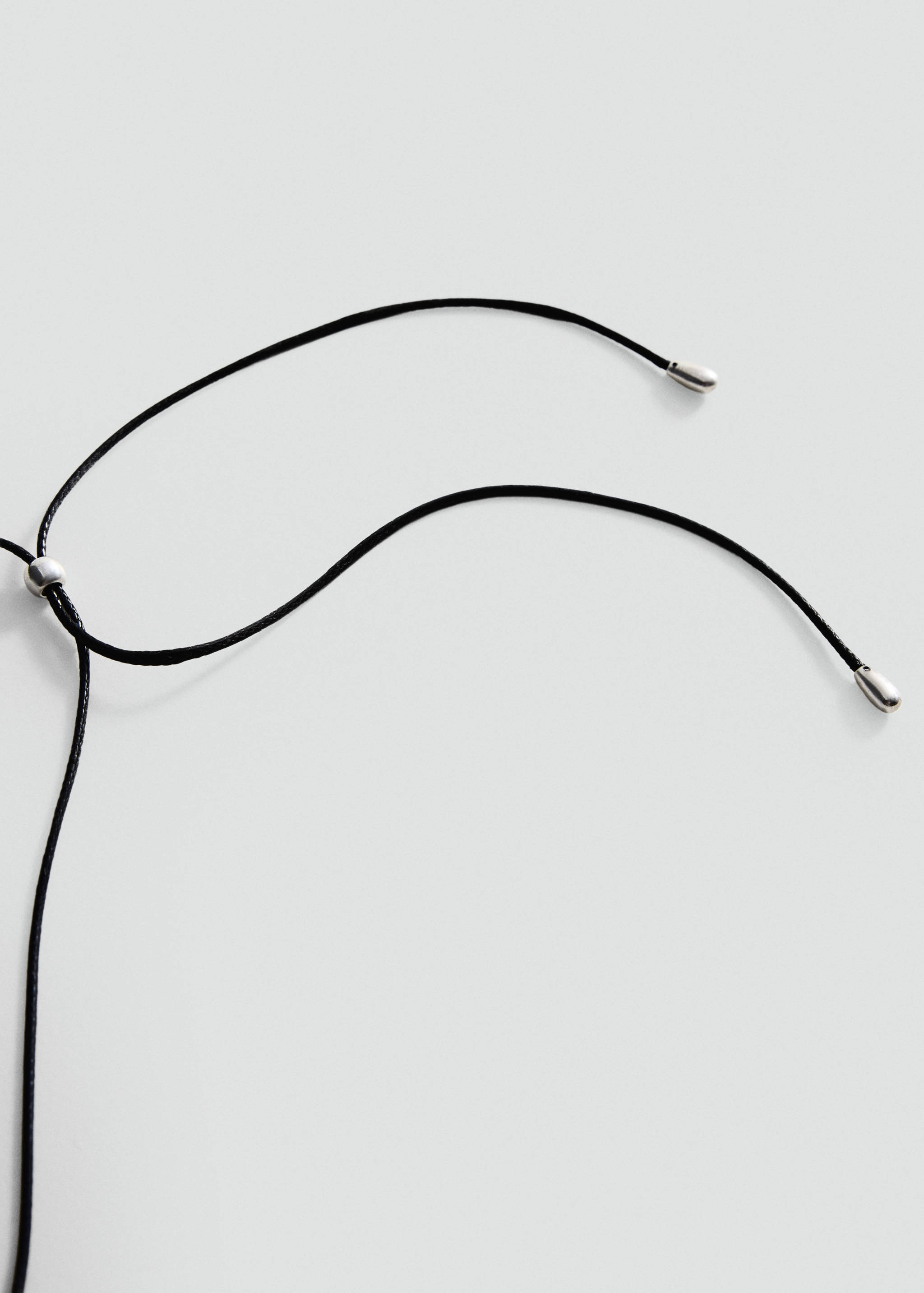 Close-up of an adjustable black cord necklace with metallic silver-toned tips.