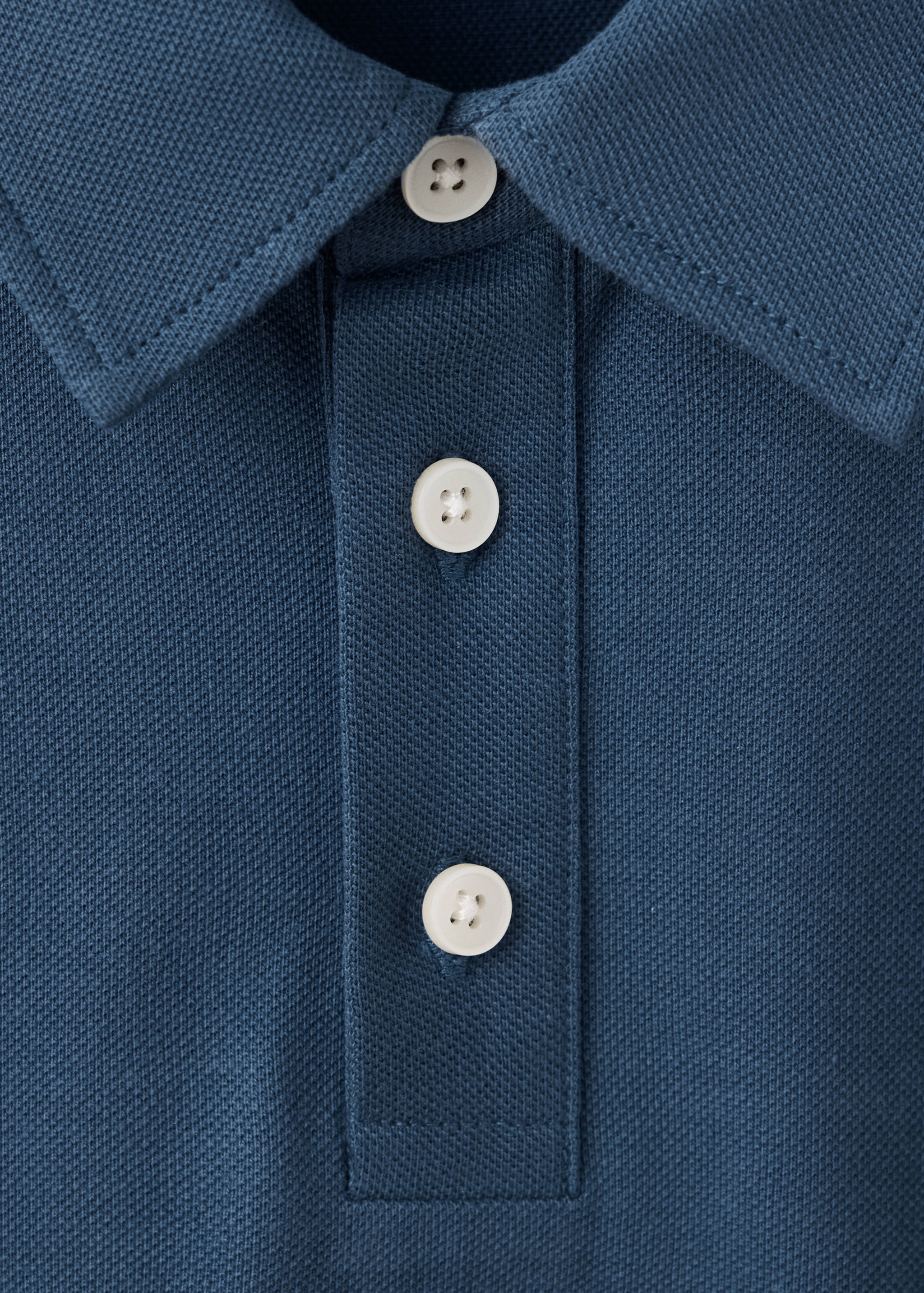 Close-up of the collar and buttoned placket on a blue polo shirt.