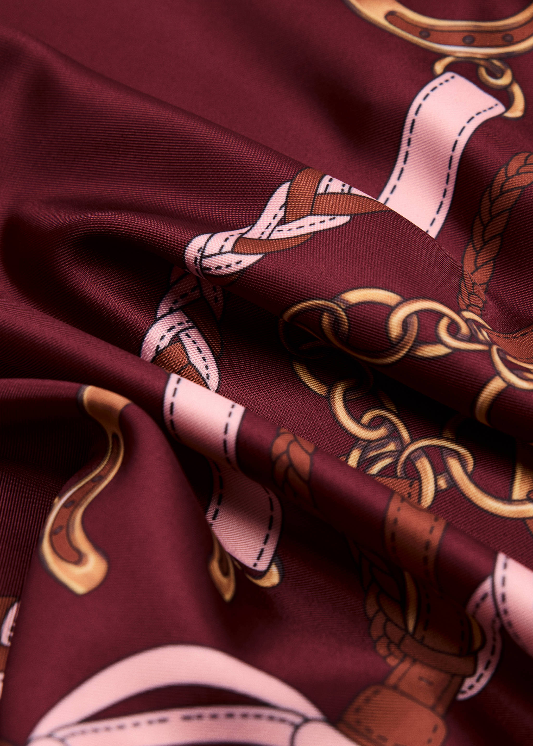 Burgundy silky scarf with an equestrian print of gold chains and pink ribbons.