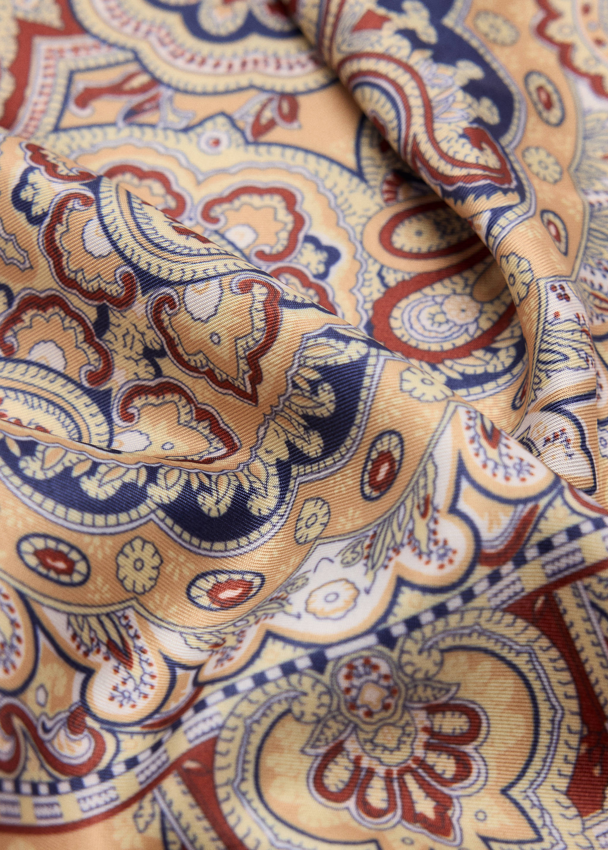 Close-up of a paisley scarf in ochre yellow, deep blue, and red.