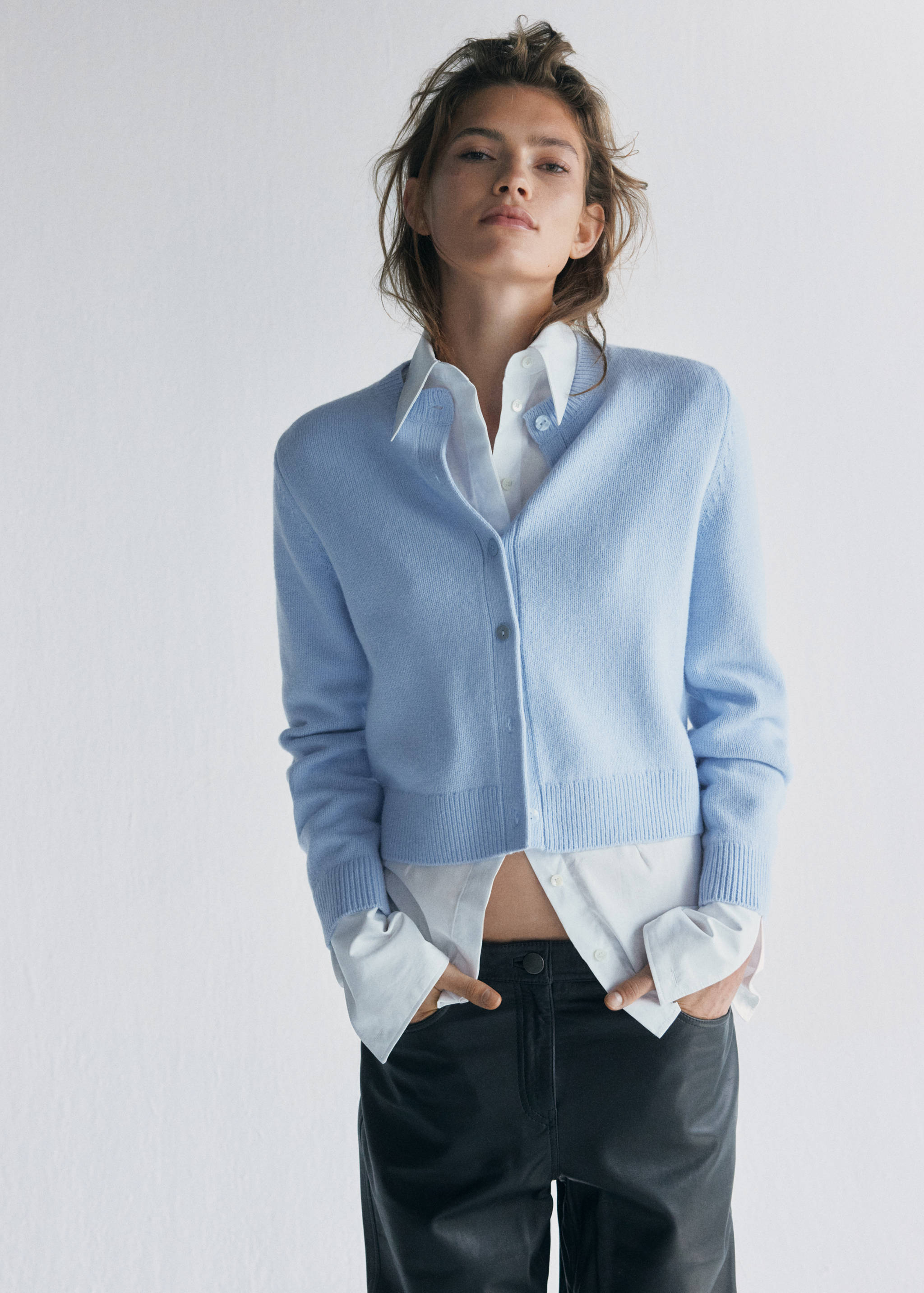 Light blue crew-neck cardigan in a cropped fit worn over a white shirt.