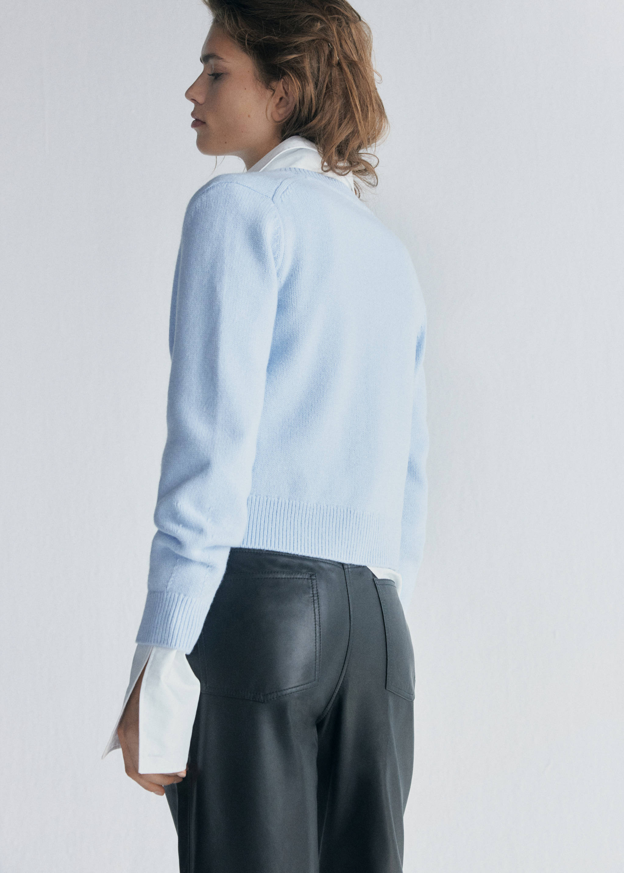 Light blue cardigan viewed from the back, worn over a white shirt.
