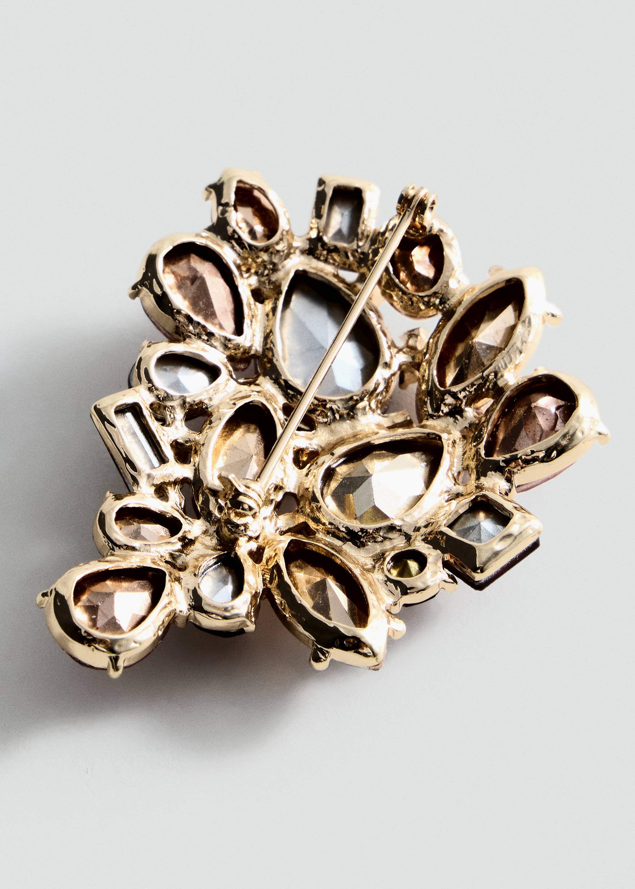 Close-up of the reverse side of an ornate gold-tone brooch showing the pin fastening.