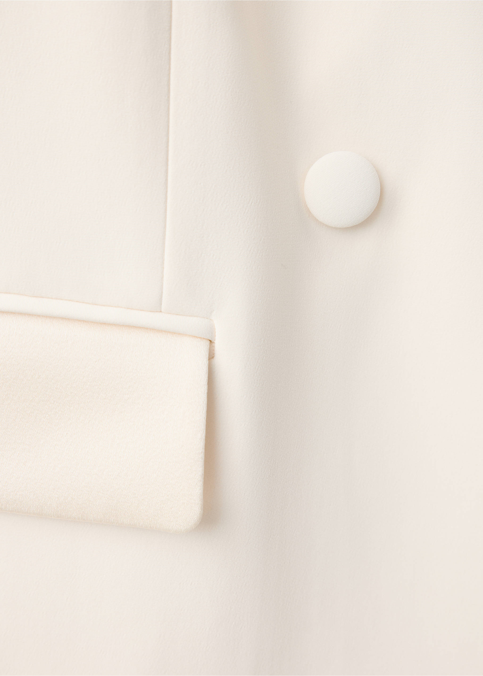 Close-up of a cream blazer showing a fabric button and flap pocket., Ecru. Ref: 47061470-00.