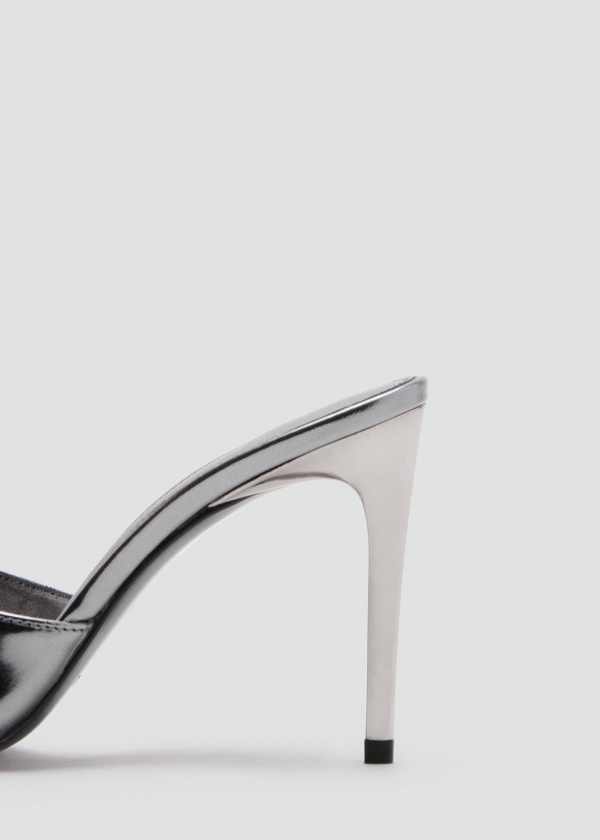 Close-up of the metallic silver stiletto heel on a sandal.