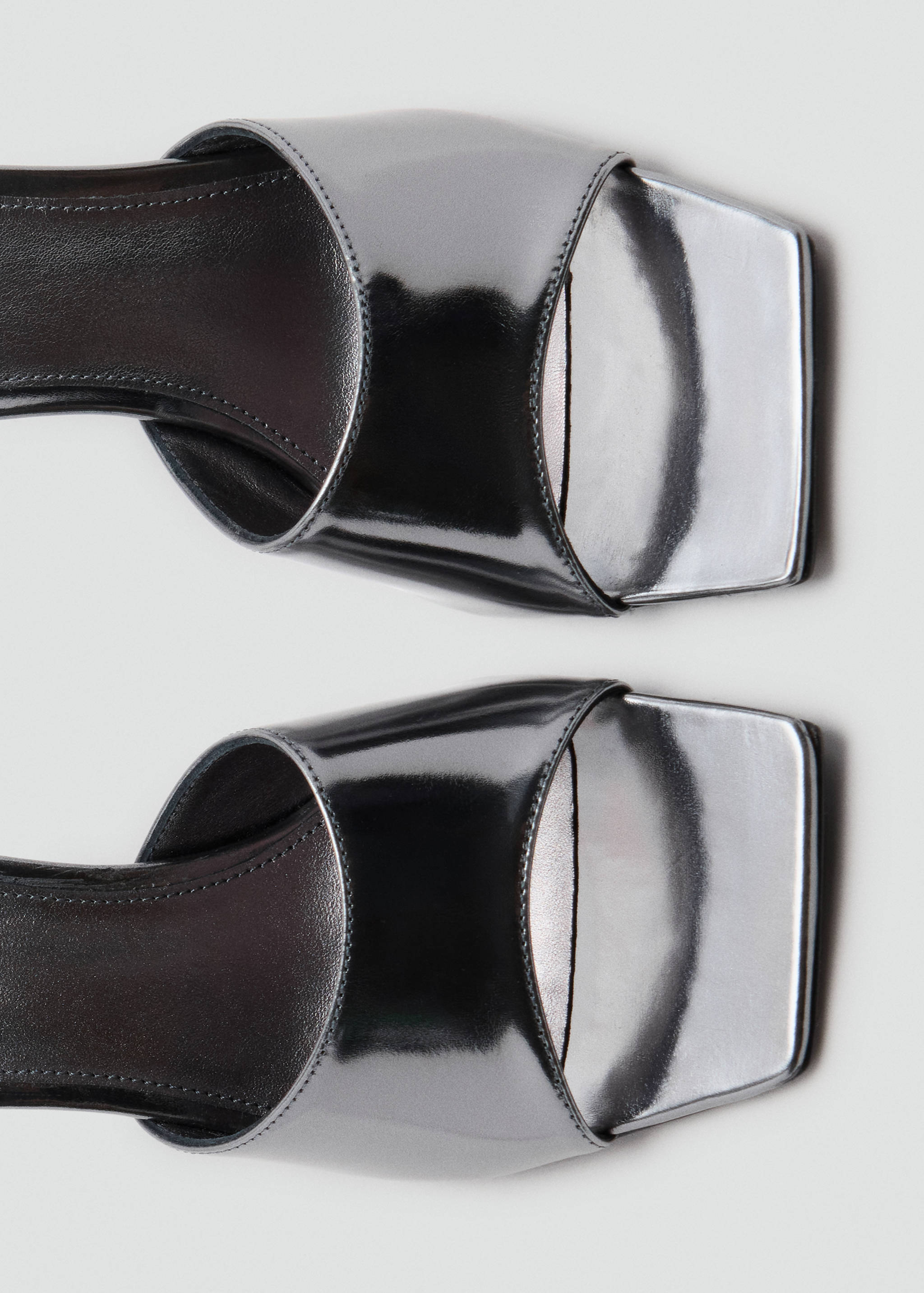 Close-up of metallic silver sandals with a square toe.