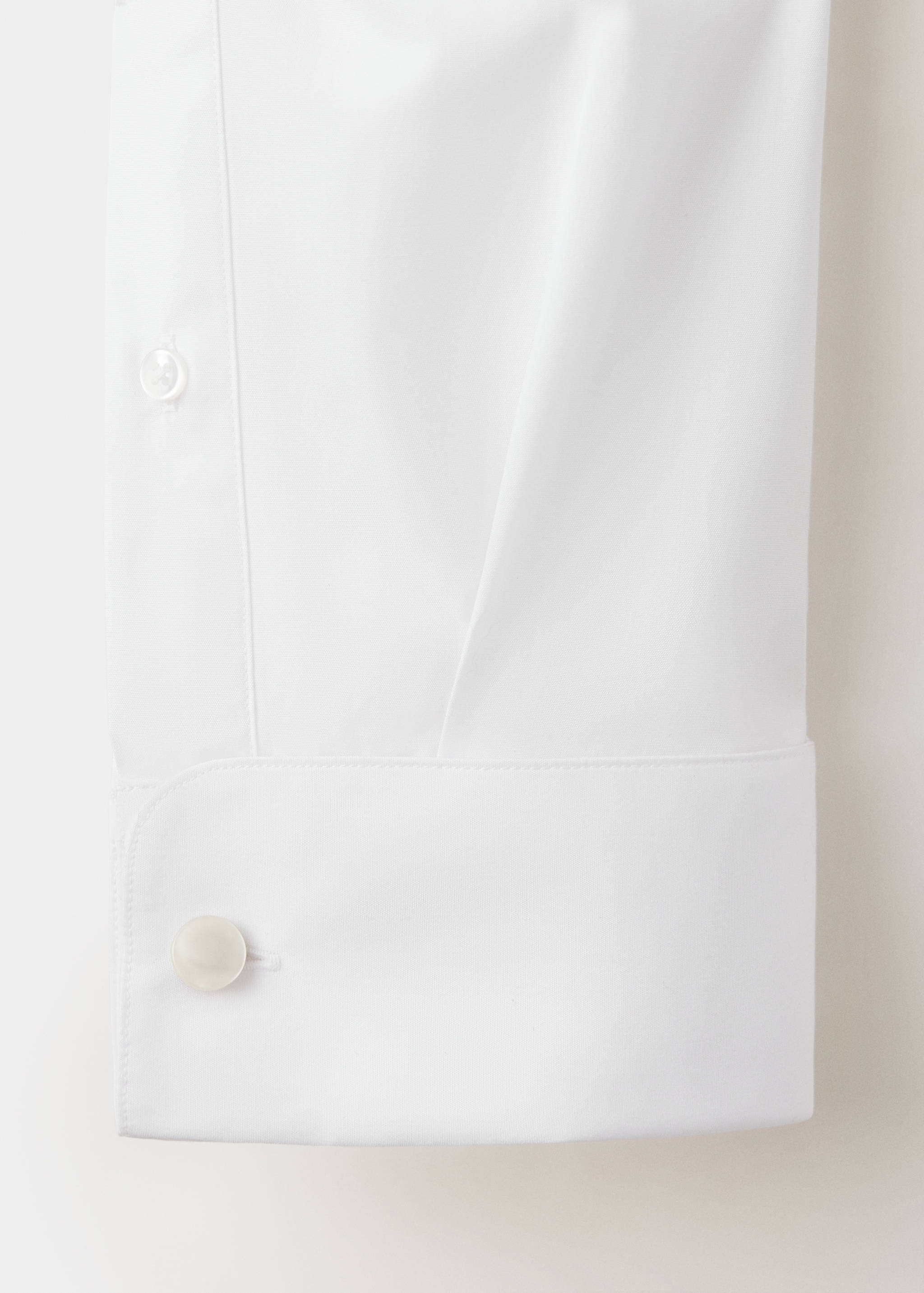 Close-up of a white men's shirt sleeve cuff and button detail.