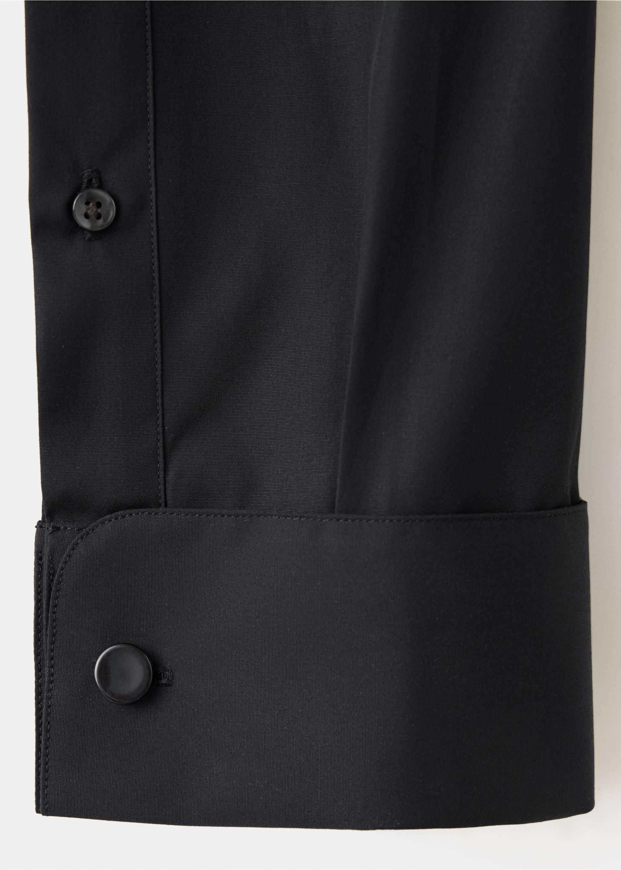 Close-up of a black shirt fabric detail showing the sleeve cuff and buttons., Black. Ref: 47071335-00.