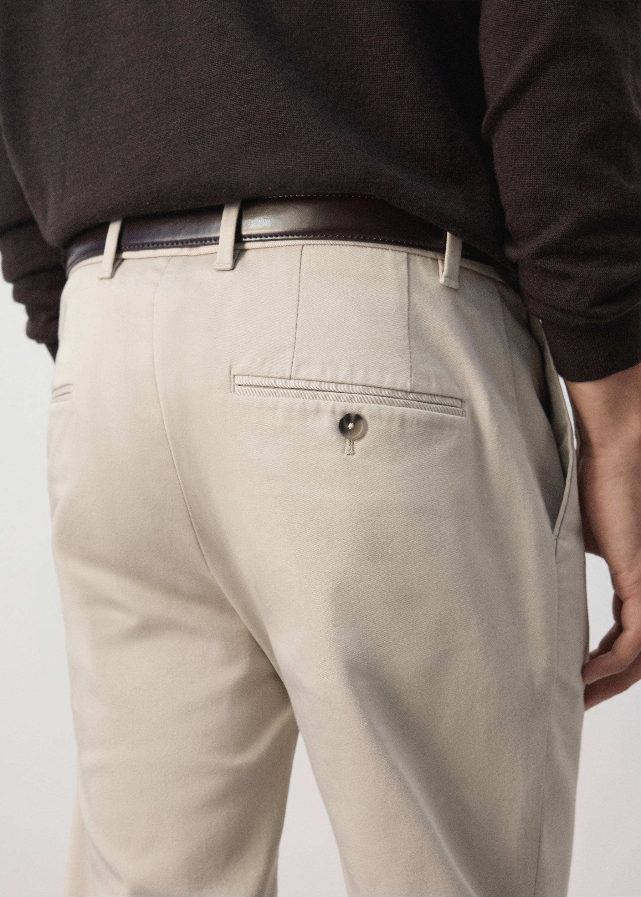 Beige trousers with a buttoned back pocket detail, worn with a dark brown belt., Ecru. Ref: 47071351-00.