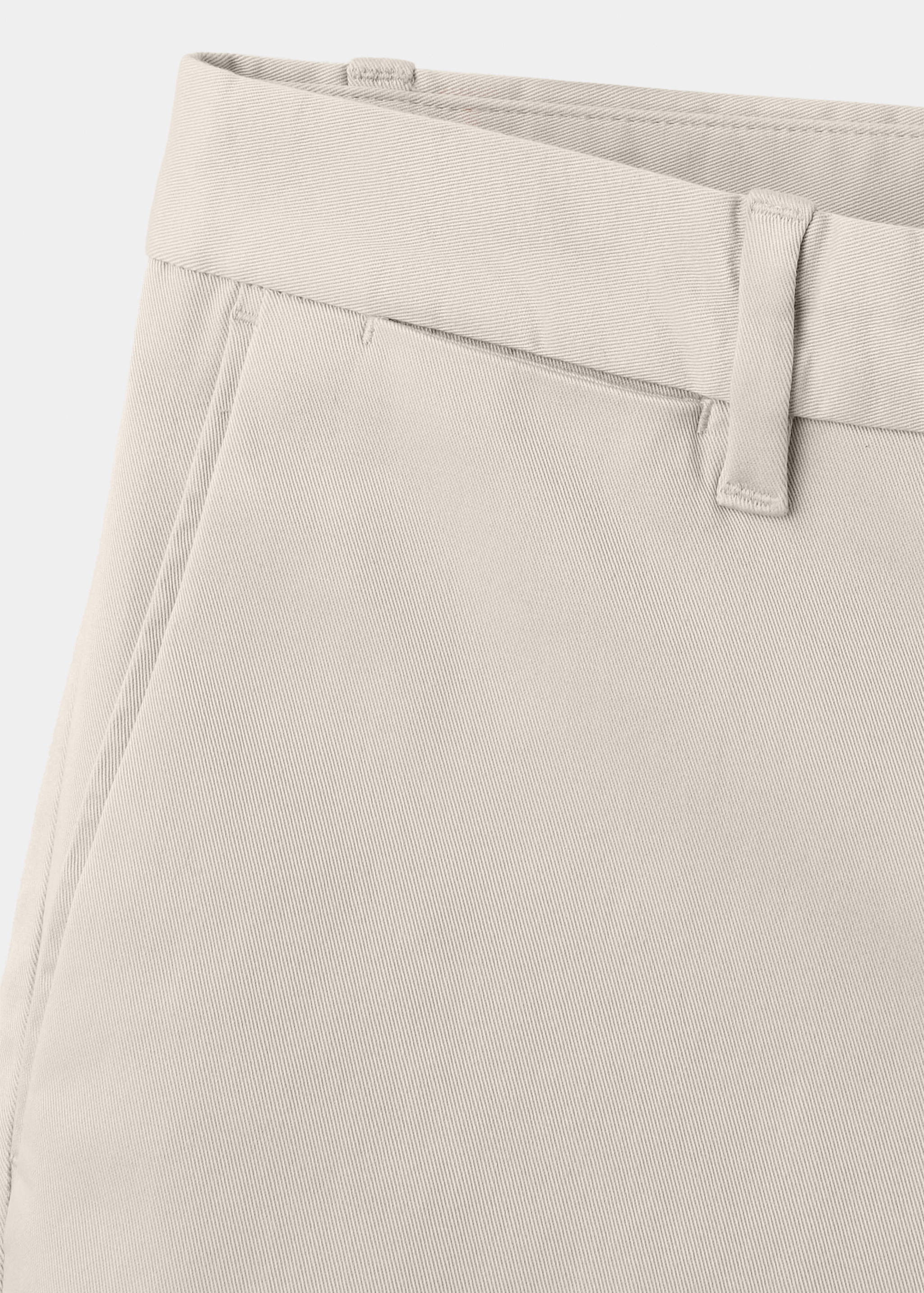 Beige trousers detail showing the waistband and pocket.