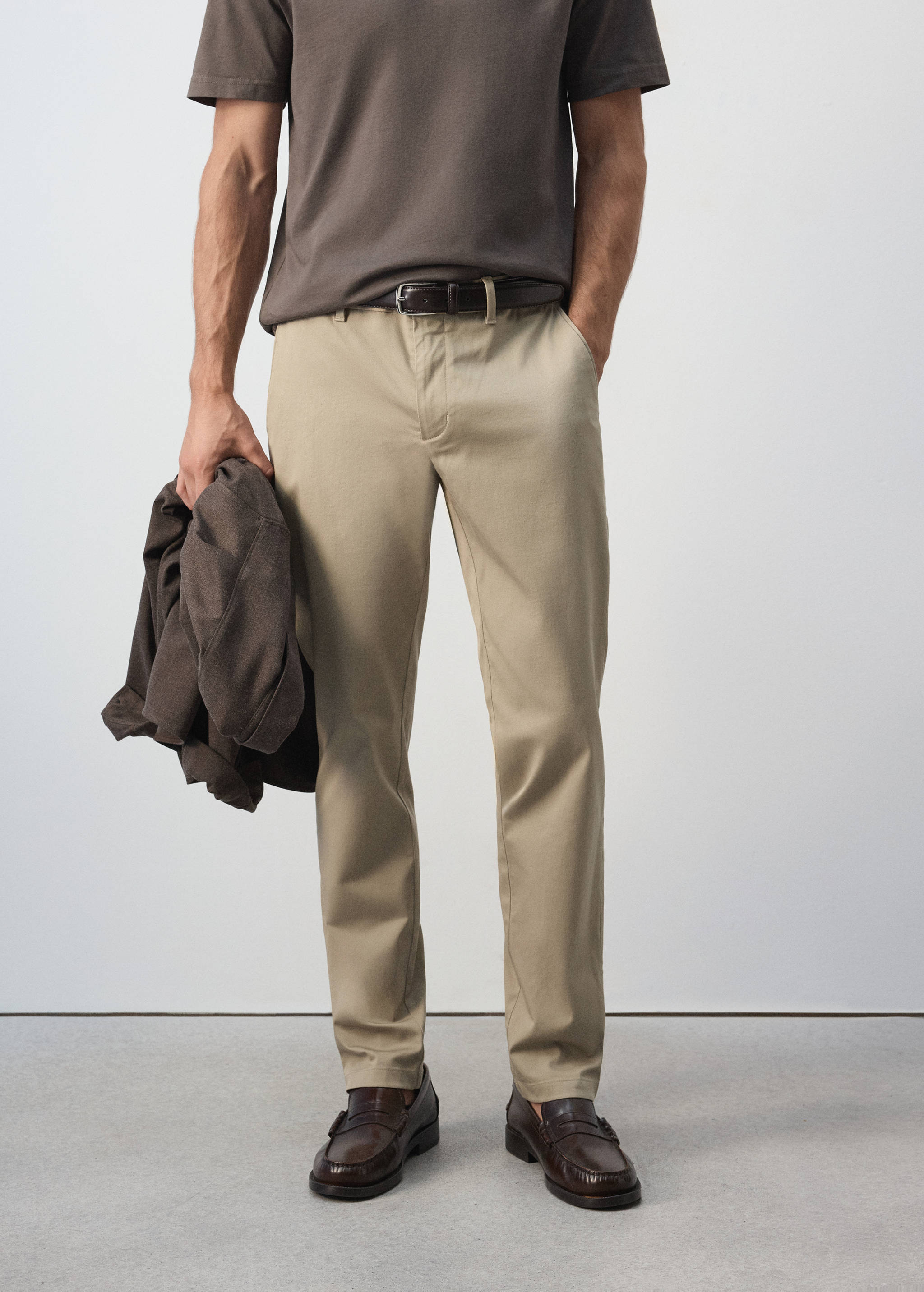 Beige slim-fit trousers with belt loops, worn with a dark brown belt and loafers.